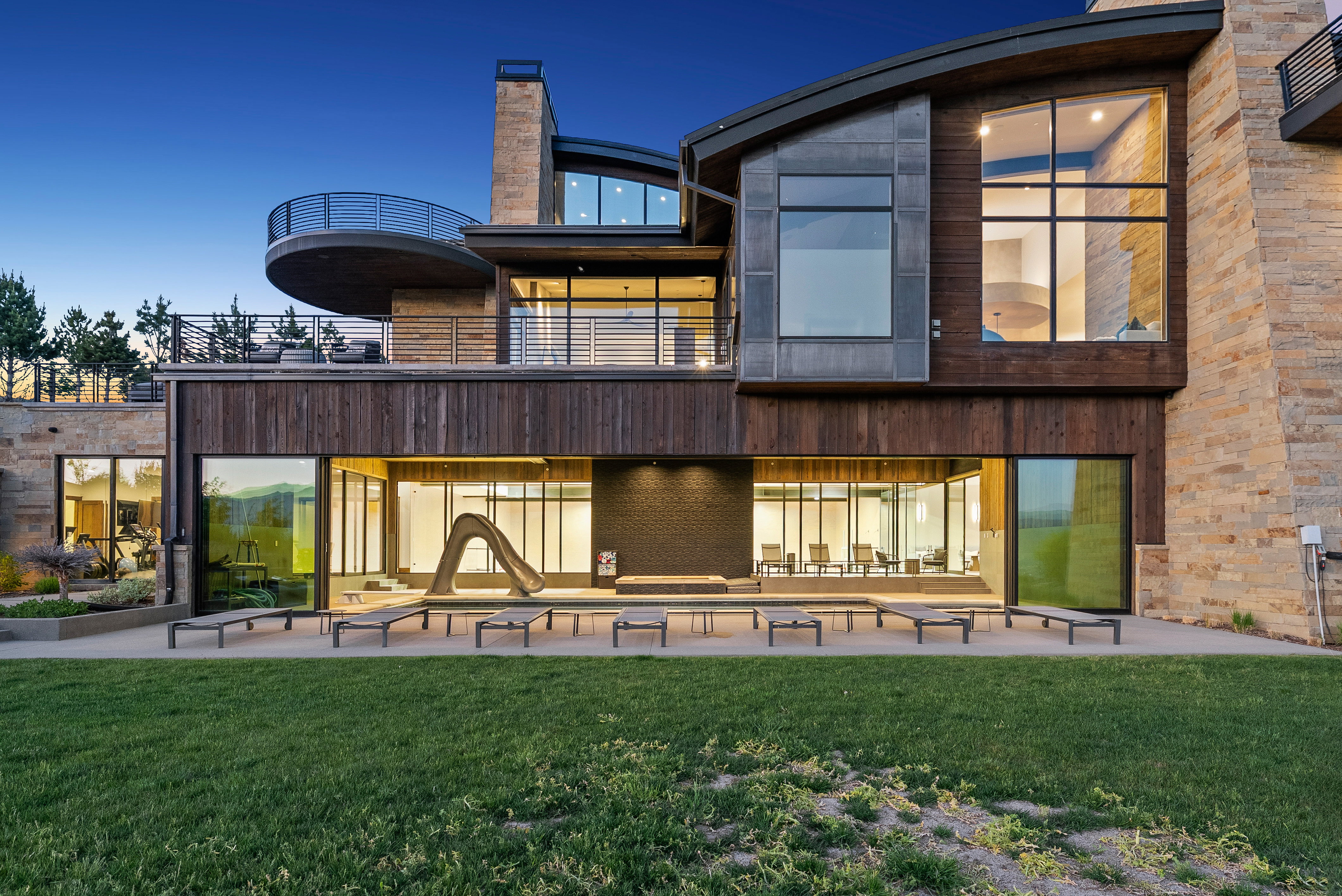 Modern architectural design featuring expansive glass panels, wood-finish siding, and stone cladding