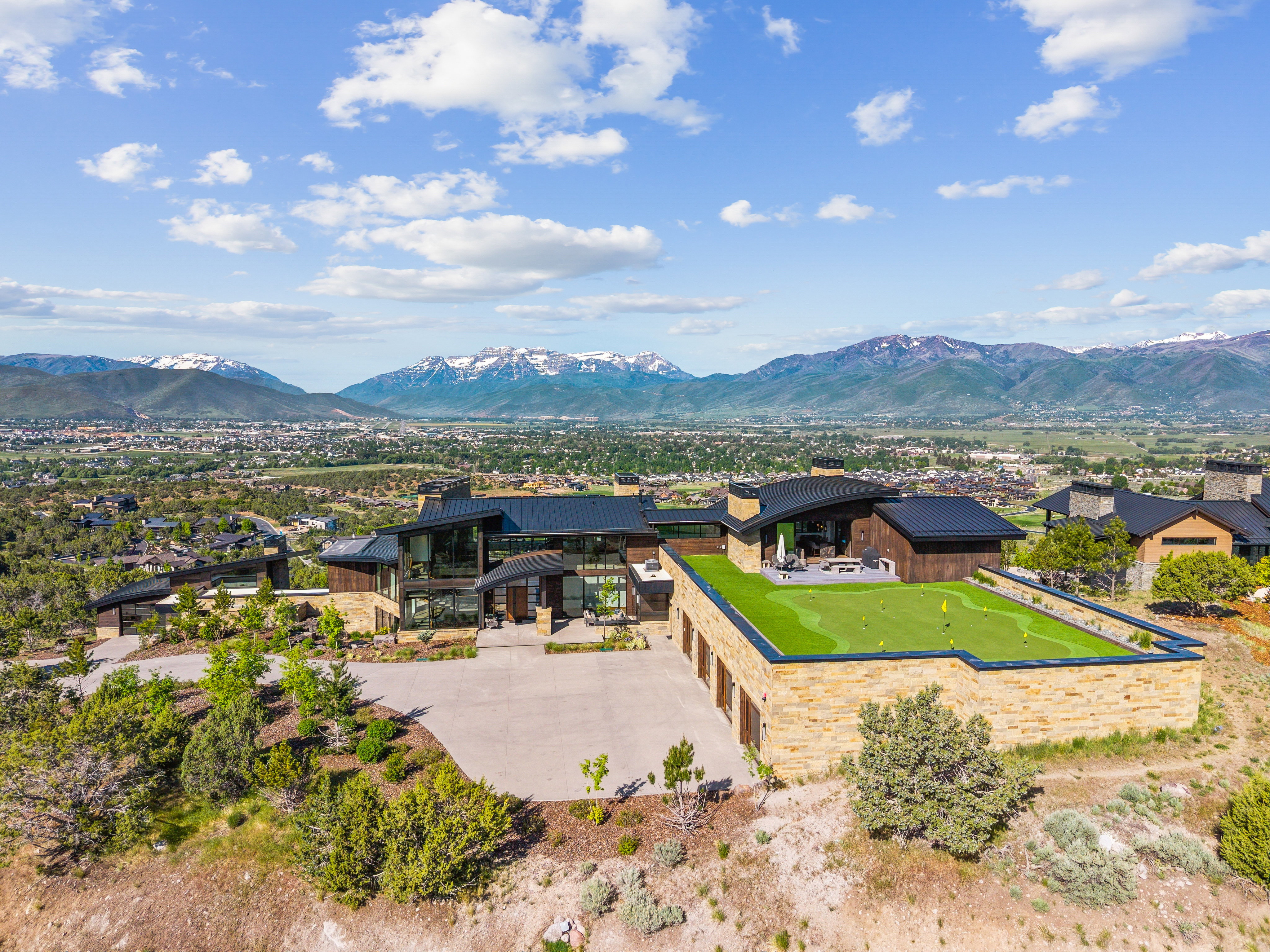 Modern mountain residence with a multi-car garage, expansive putting green, and stone exterior