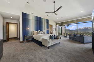 Spacious bedroom featuring large format windows, a contemporary ceiling fan, recessed lighting, and a striking paneled accent wall