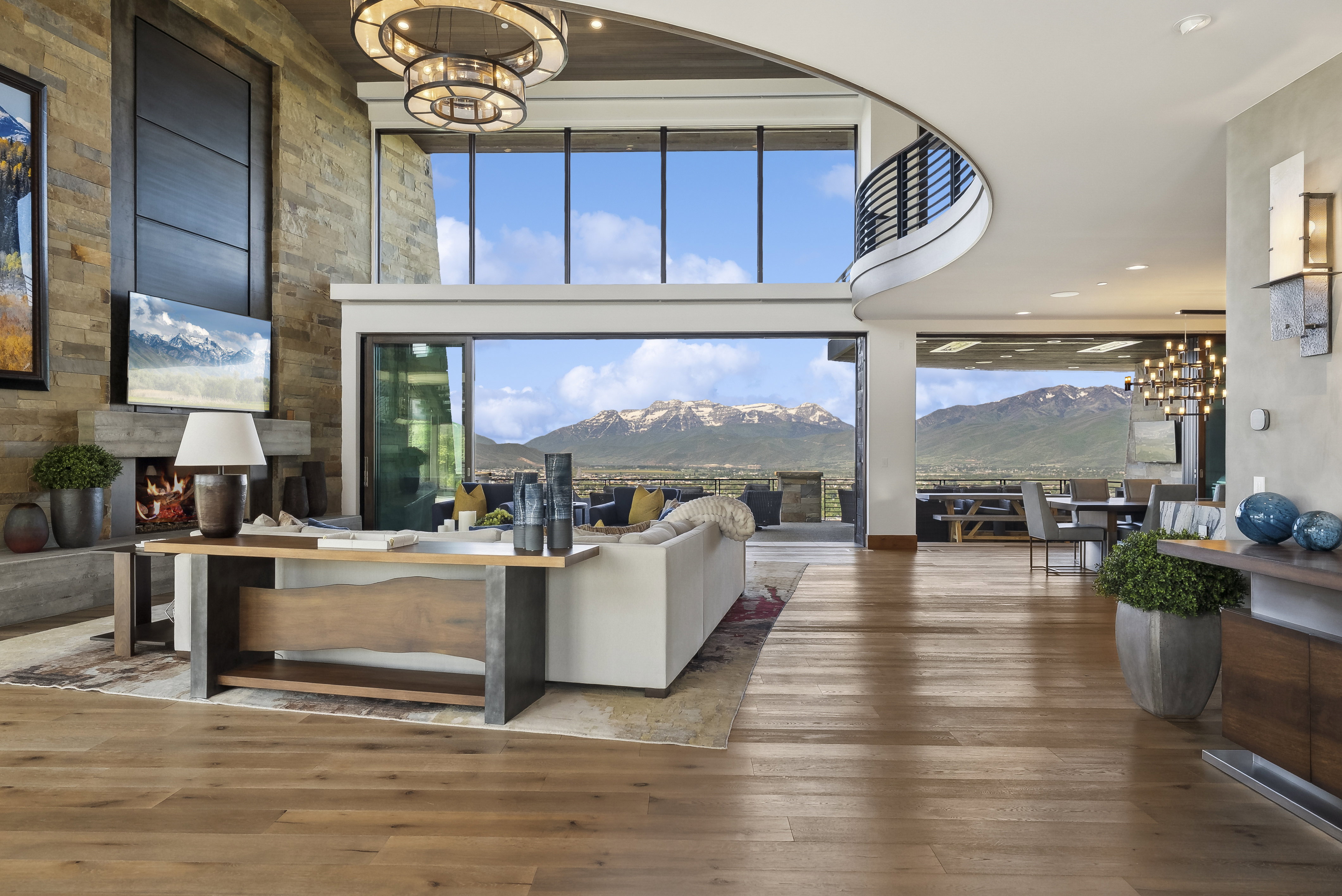 Expansive living space featuring wood-finish flooring and a stone accent wall with a fireplace