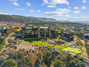 Expansive contemporary residence featuring multiple levels of outdoor living space, a terraced lawn, and a private putting green