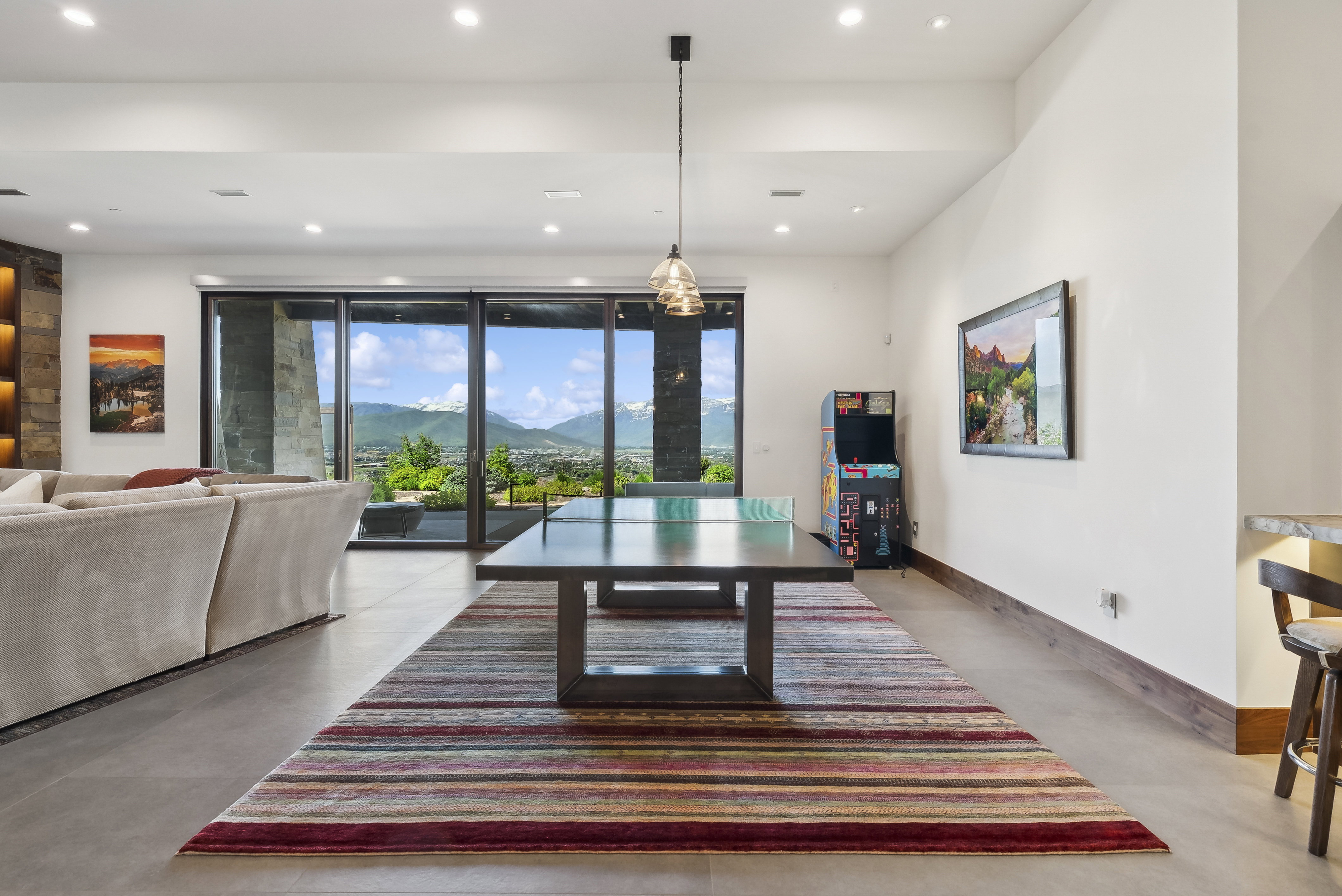 Open-concept room featuring floor-to-ceiling sliding glass doors, recessed lighting, and a stone accent wall with built-in shelving