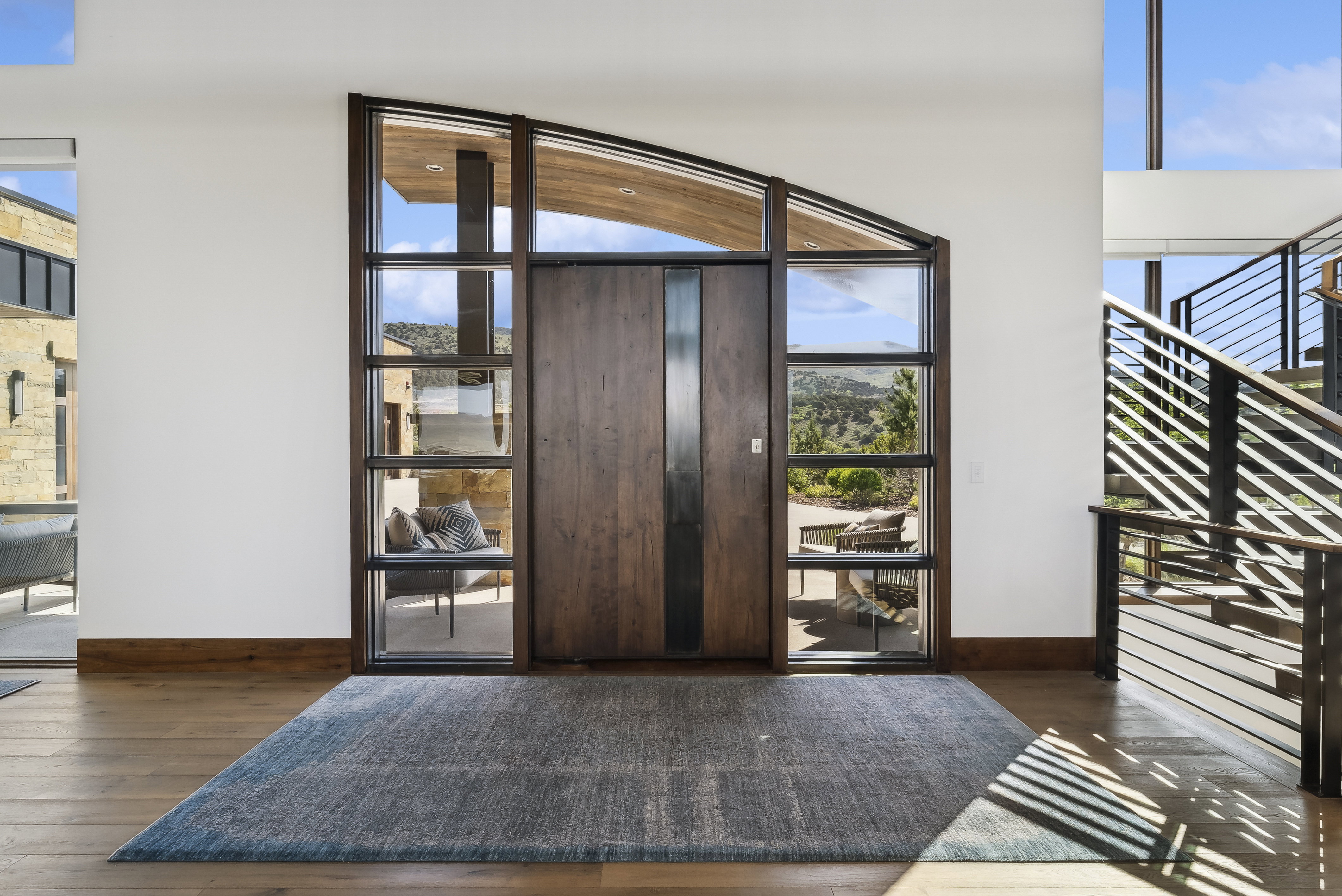 Grand entry featuring a solid wood door with vertical accent panels, expansive sidelight windows, and a curved transom