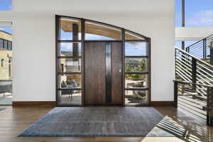 Grand entry featuring a solid wood door with vertical accent panels, expansive sidelight windows, and a curved transom