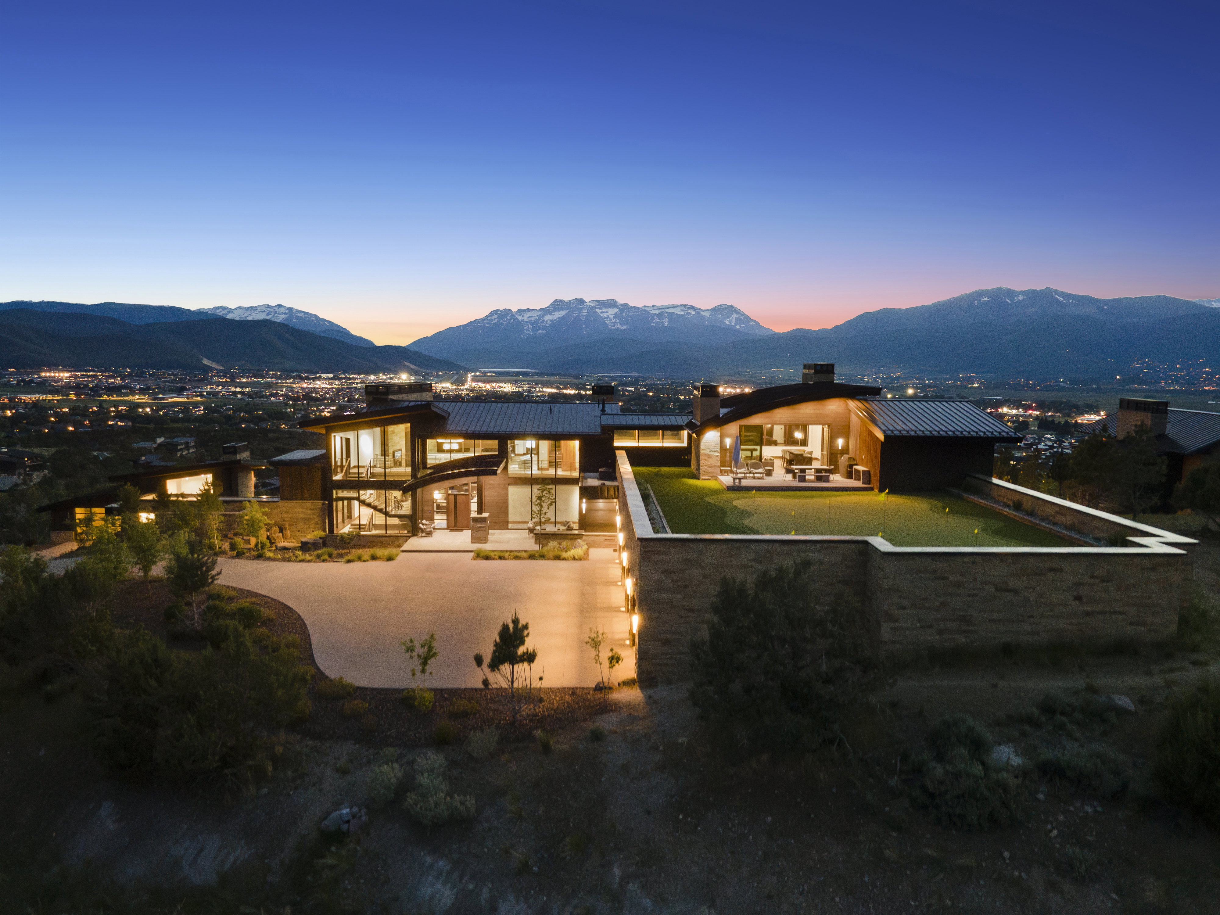 Modern architecture featuring extensive glazing, a multi-level design, and a large putting green