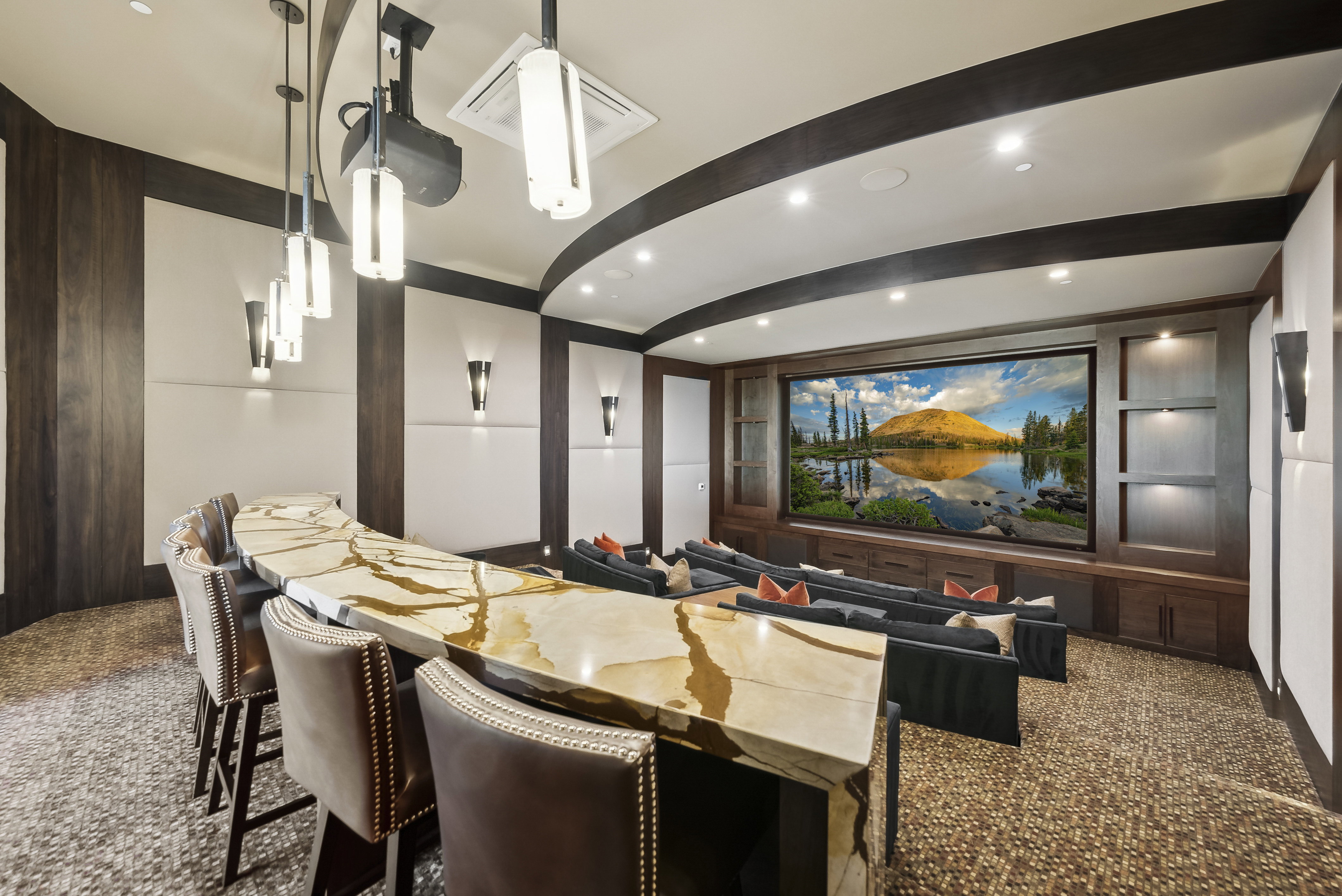 Dedicated home theater featuring a large projection screen, tiered seating, and integrated media cabinetry