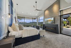 Spacious bedroom featuring floor-to-ceiling windows, a linear gas fireplace, a large concrete-finish accent wall, and a full-light entry door