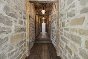 Stone-clad hallway featuring wood-finish flooring and exposed timber ceiling beams