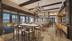 Open-concept interior featuring wood-finish flooring, exposed ceiling beams, a striking chandelier, and floor-to-ceiling windows with mountain scenery