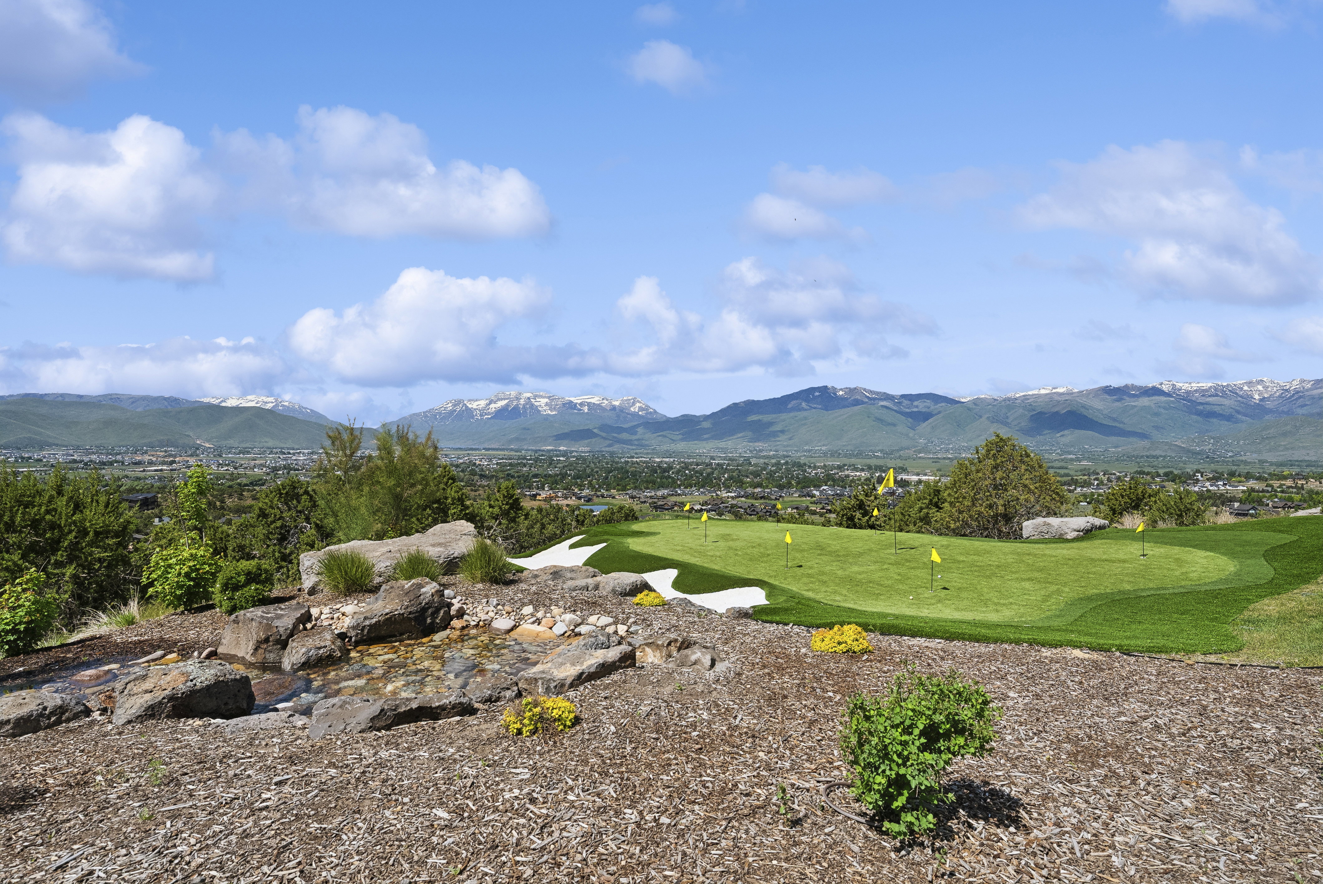 Private putting green with multiple holes, sand traps, and a surrounding natural landscape