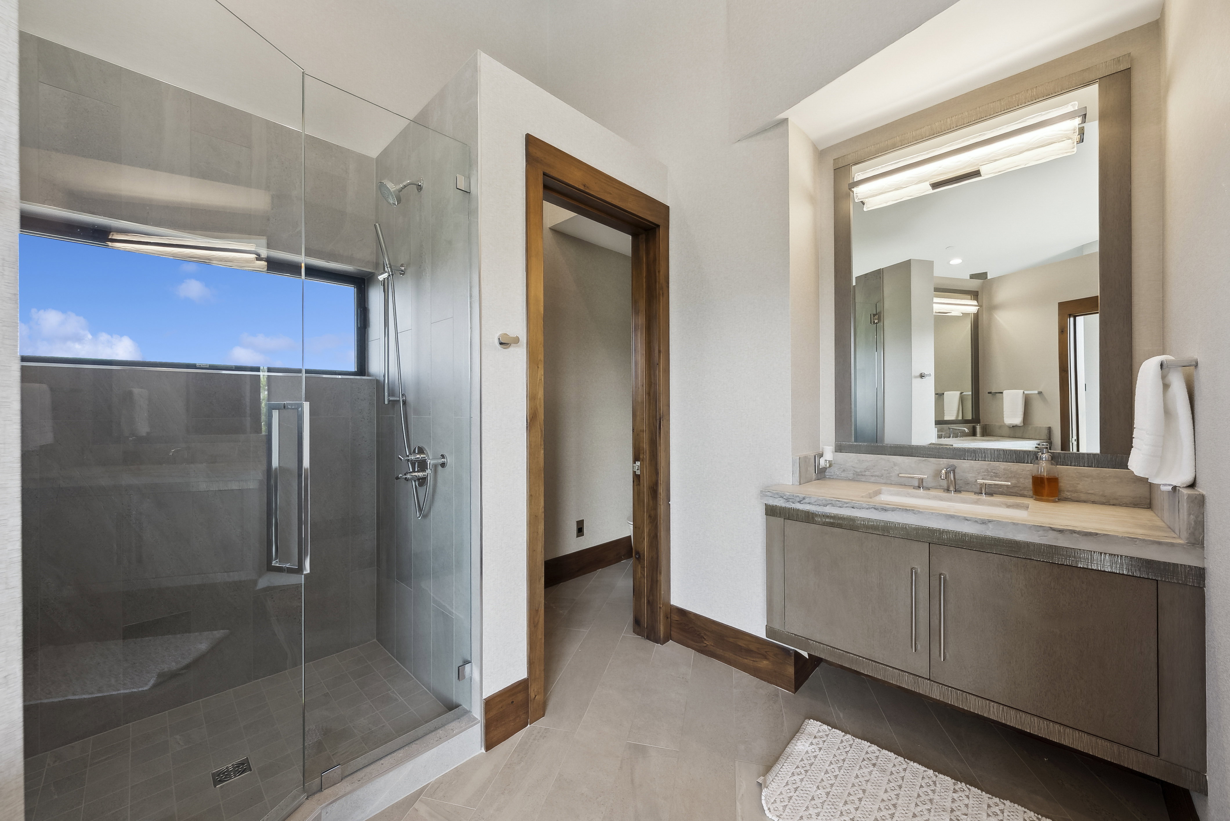 Glass-enclosed shower with a linear window and built-in shower bench