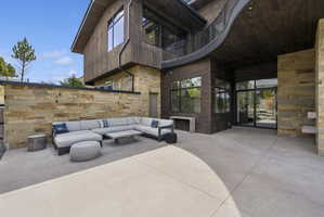 Expansive concrete patio with a stone retaining wall and wood-paneled exterior