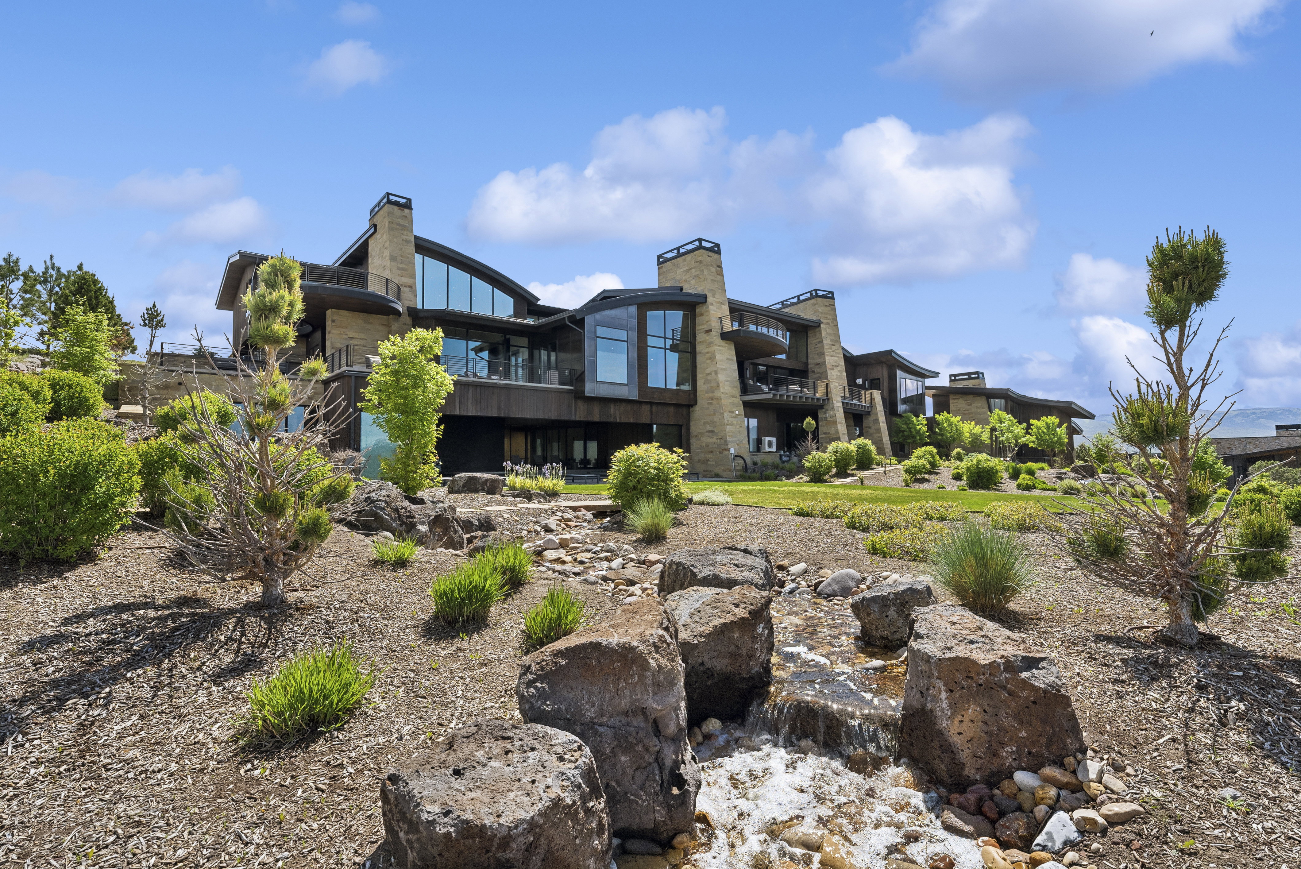 Contemporary architectural design featuring extensive stonework and dark wood siding