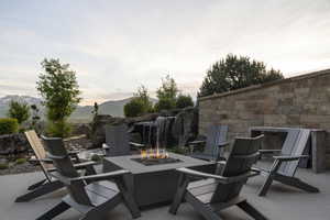 Outdoor entertaining area featuring a built-in fire pit, a stacked stone retaining wall, and a multi-tiered water feature