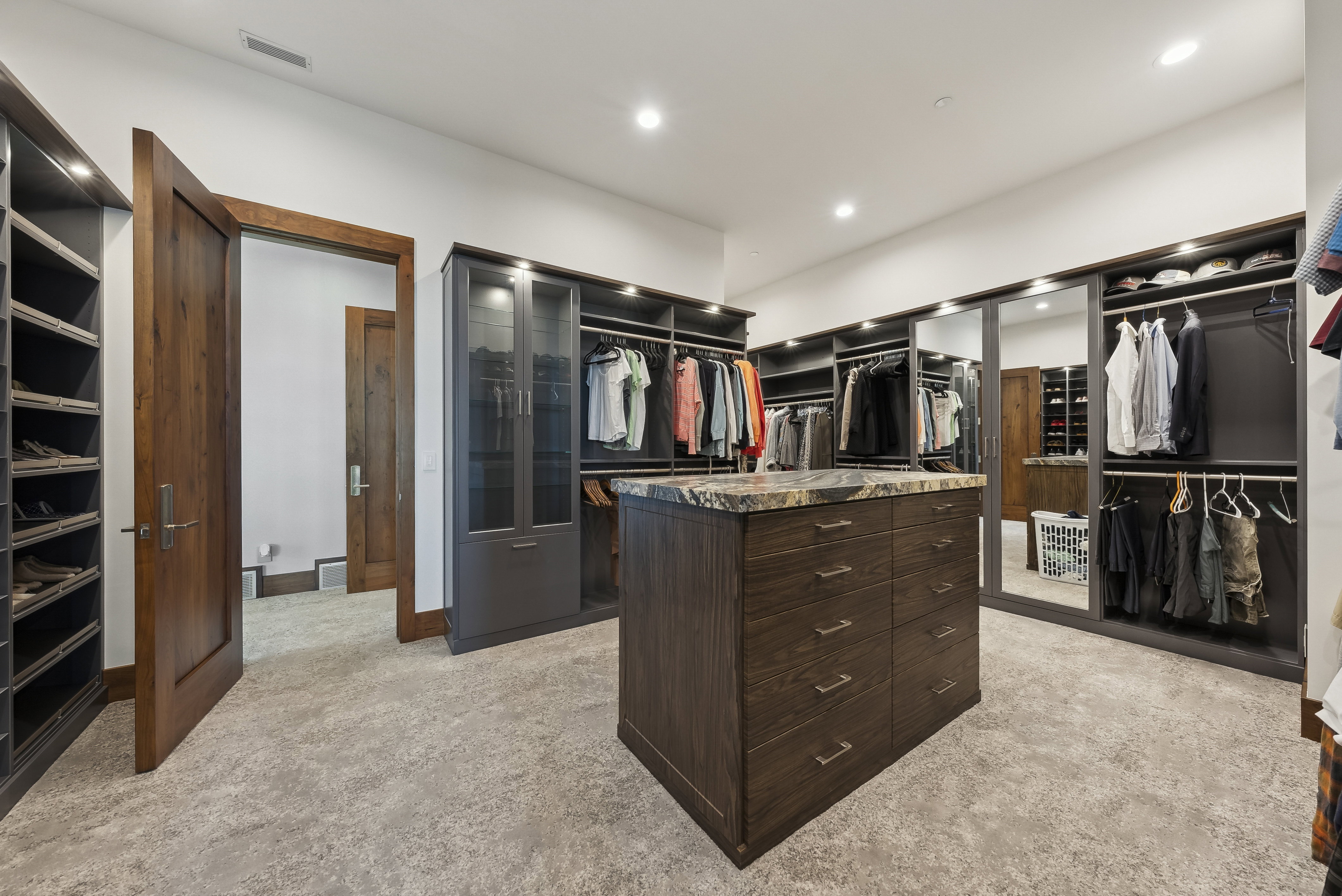 Custom closet system featuring a central island with drawers and a stone countertop