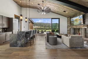 Spacious open-concept interior featuring wood-finish flooring, a vaulted wood-plank ceiling, and a stone-clad fireplace