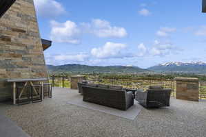 Expansive outdoor patio featuring a textured aggregate surface, a stone-clad exterior wall, and a low metal railing