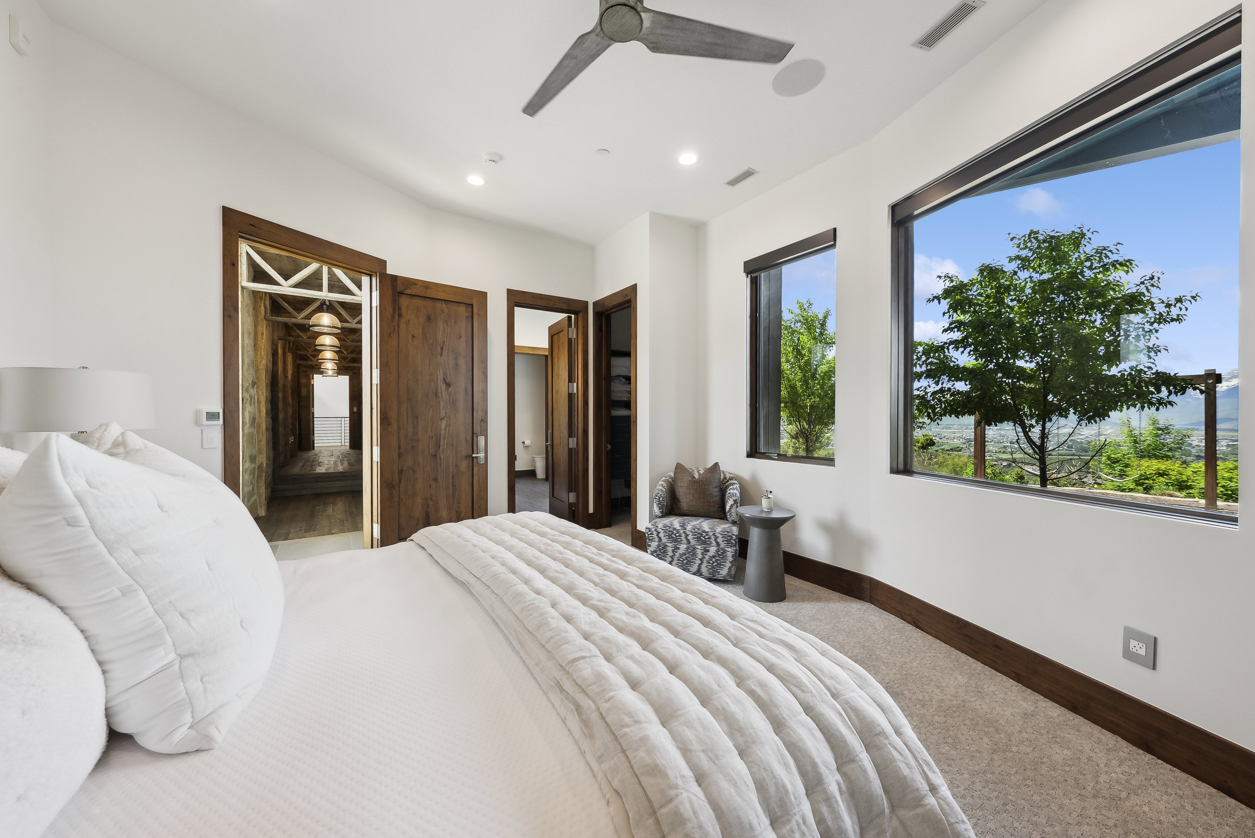 Spacious room featuring broad windows with mountain scenery, rich wood-finish doors, recessed lighting, a modern ceiling fan, and carpeted flooring