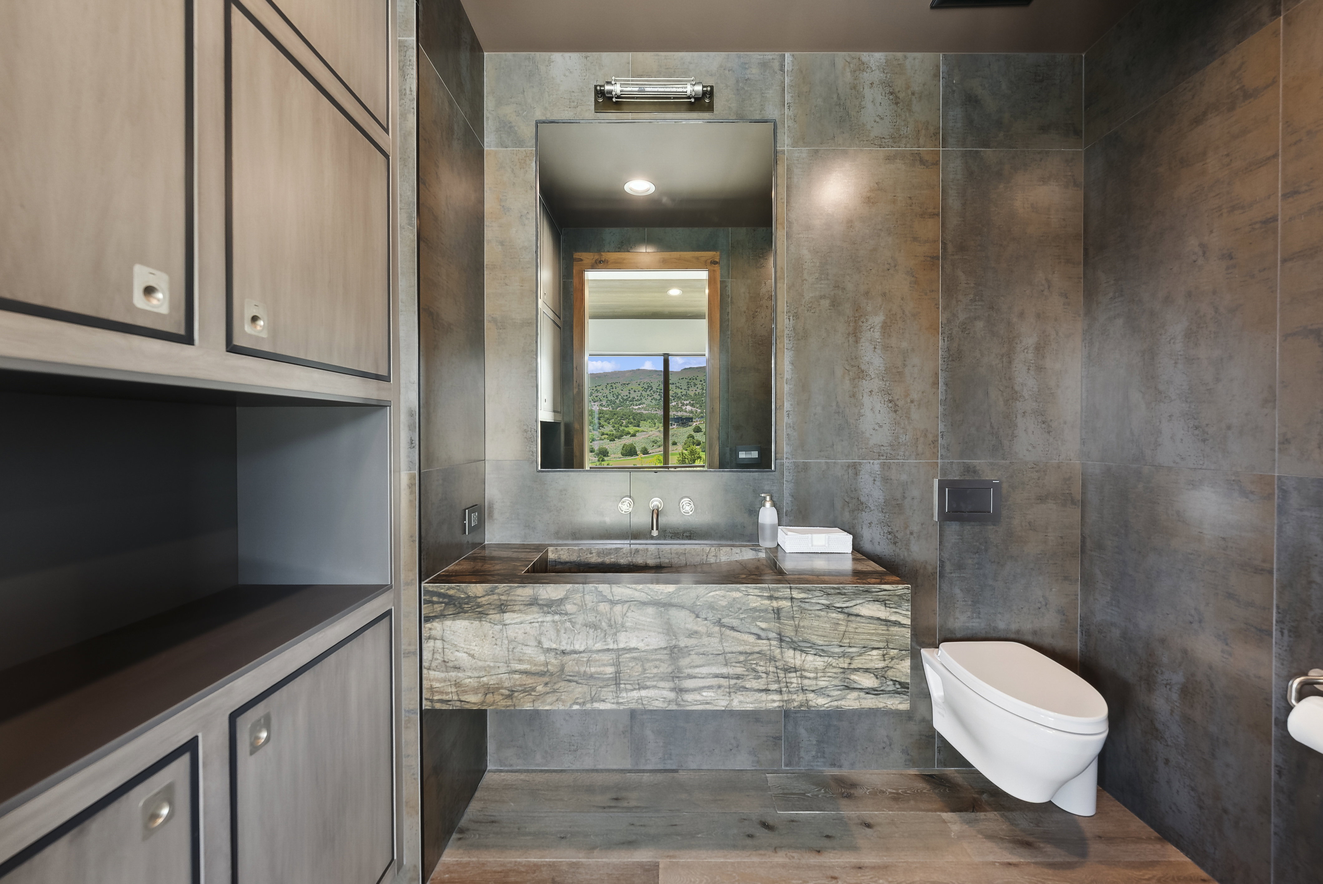Contemporary bathroom featuring a floating stone vanity with integrated sink, a wall-mounted toilet, and large format wall tiles