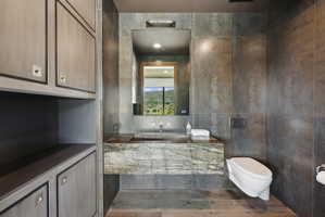 Contemporary bathroom featuring a floating stone vanity with integrated sink, a wall-mounted toilet, and large format wall tiles