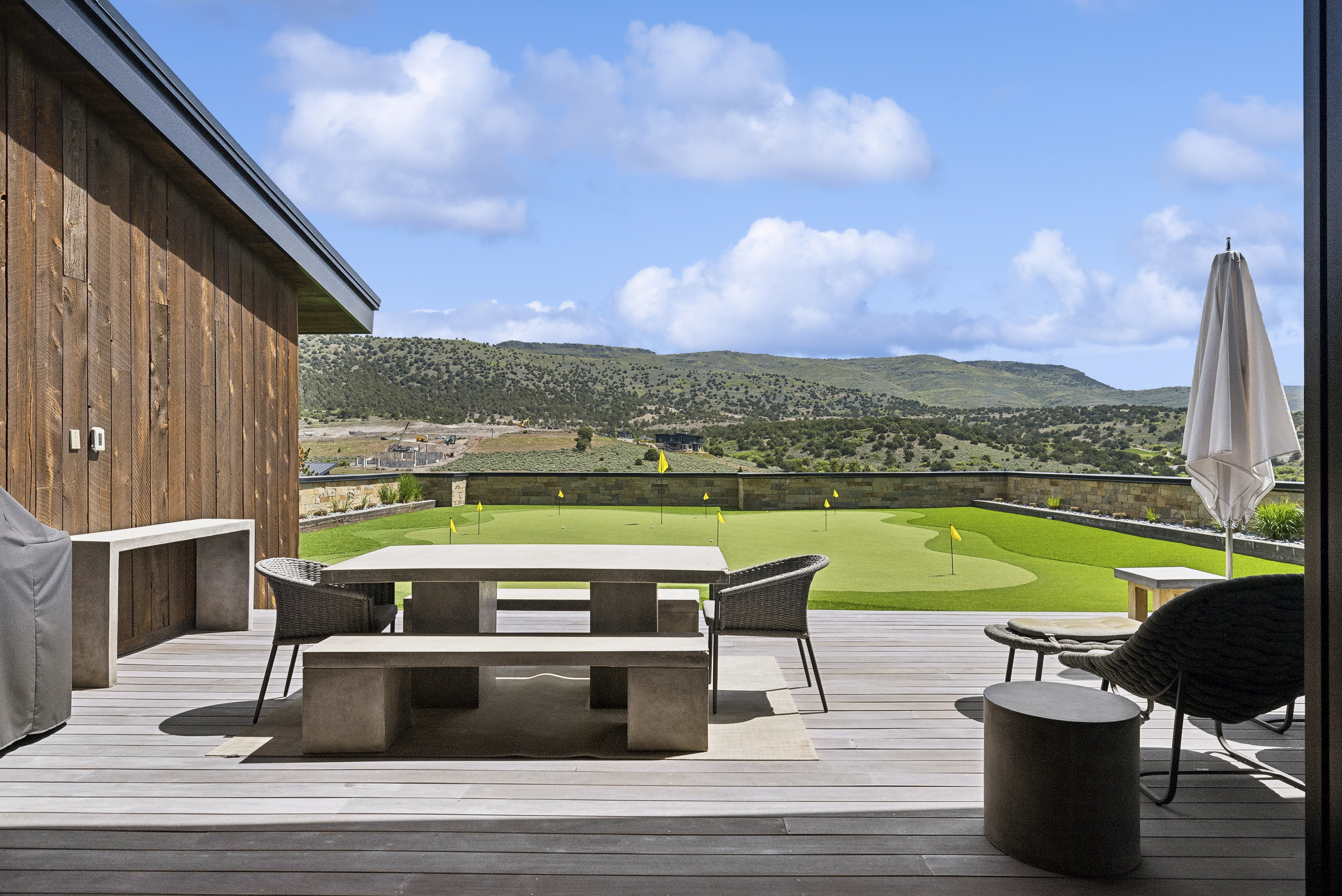 Expansive outdoor deck featuring wood-finish decking, a built-in putting green, and stone hardscaping