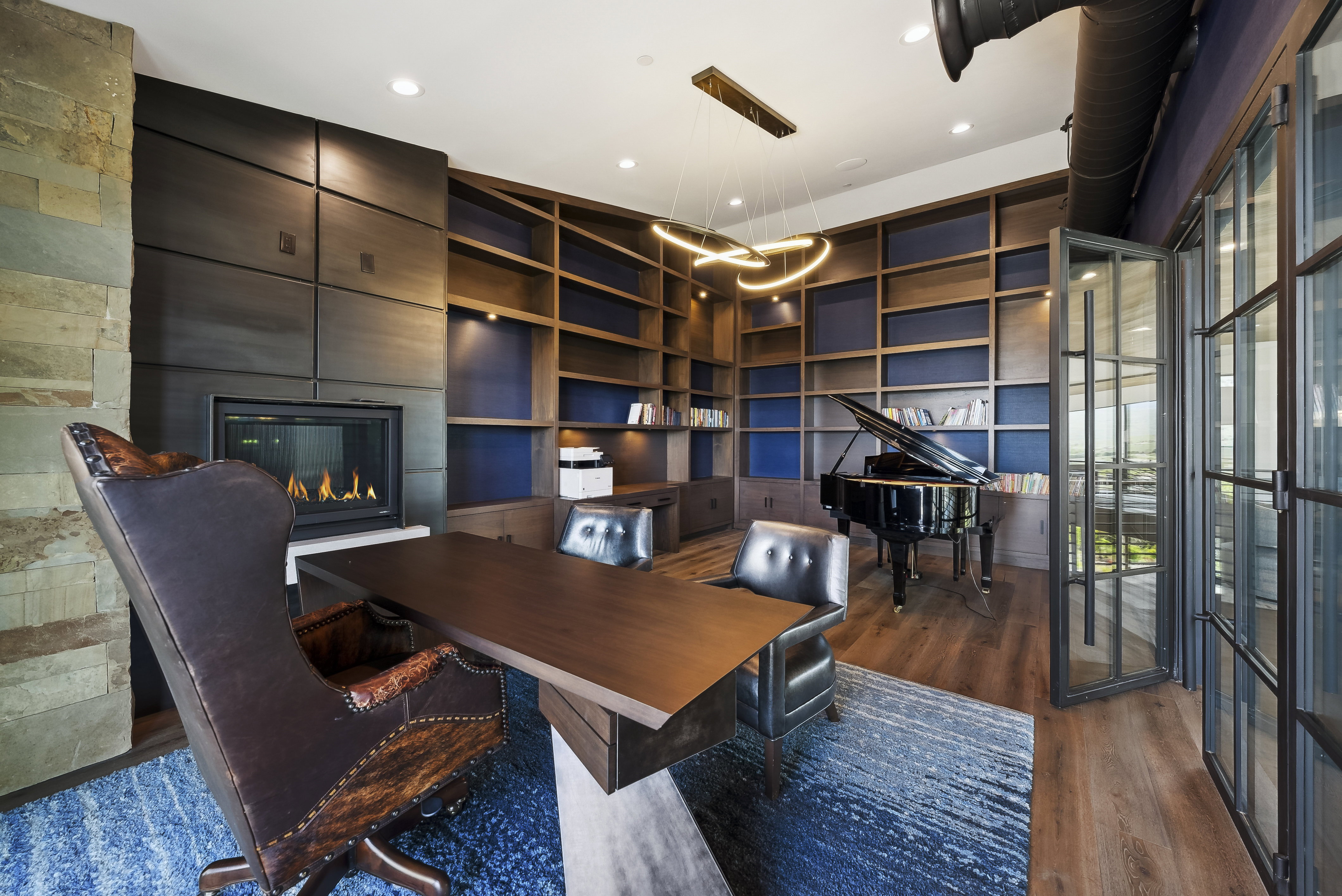Spacious room featuring extensive built-in shelving, a natural stone fireplace, and wood-finish flooring