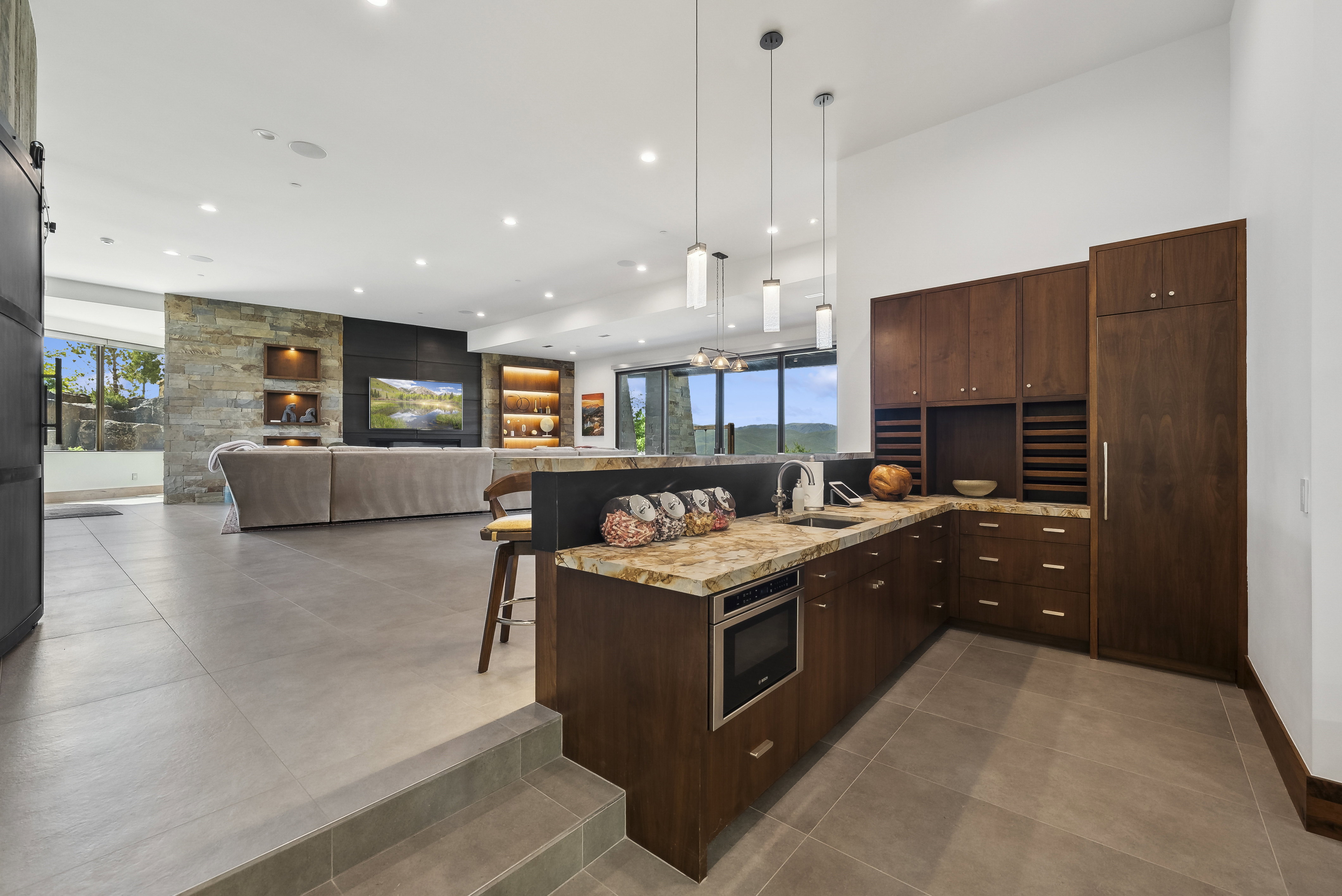 Contemporary wet bar featuring wood-finish cabinetry, stone countertops, an undermount sink, and a built-in microwave
