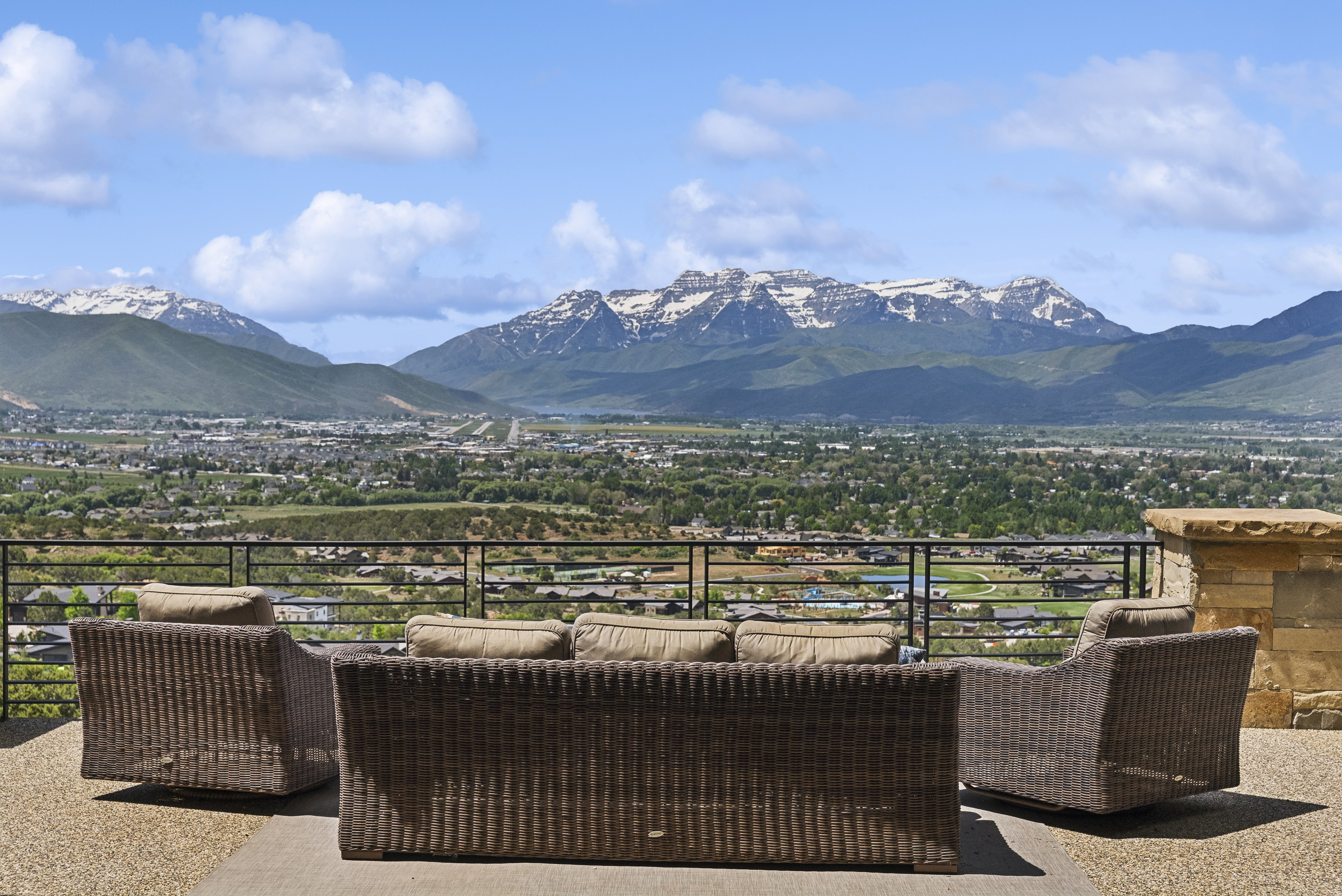 Expansive outdoor patio with stone veneer wall, black metal railing, and exposed aggregate concrete flooring