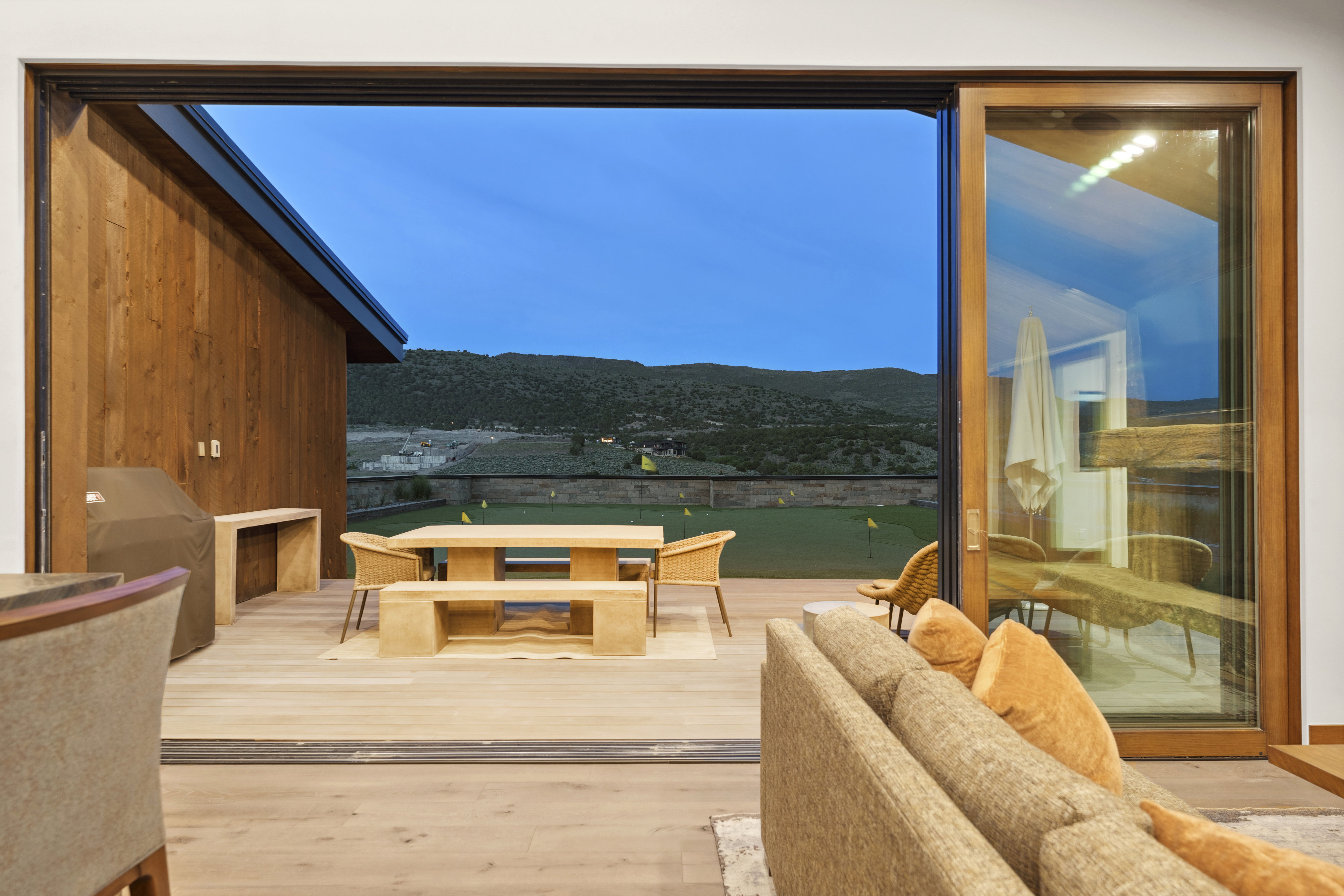 Expansive outdoor deck with wood-finish flooring, featuring a built-in stone countertop and a wood-paneled exterior wall