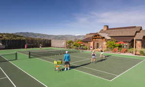 Expansive outdoor tennis courts featuring a hard court surface and perimeter fencing