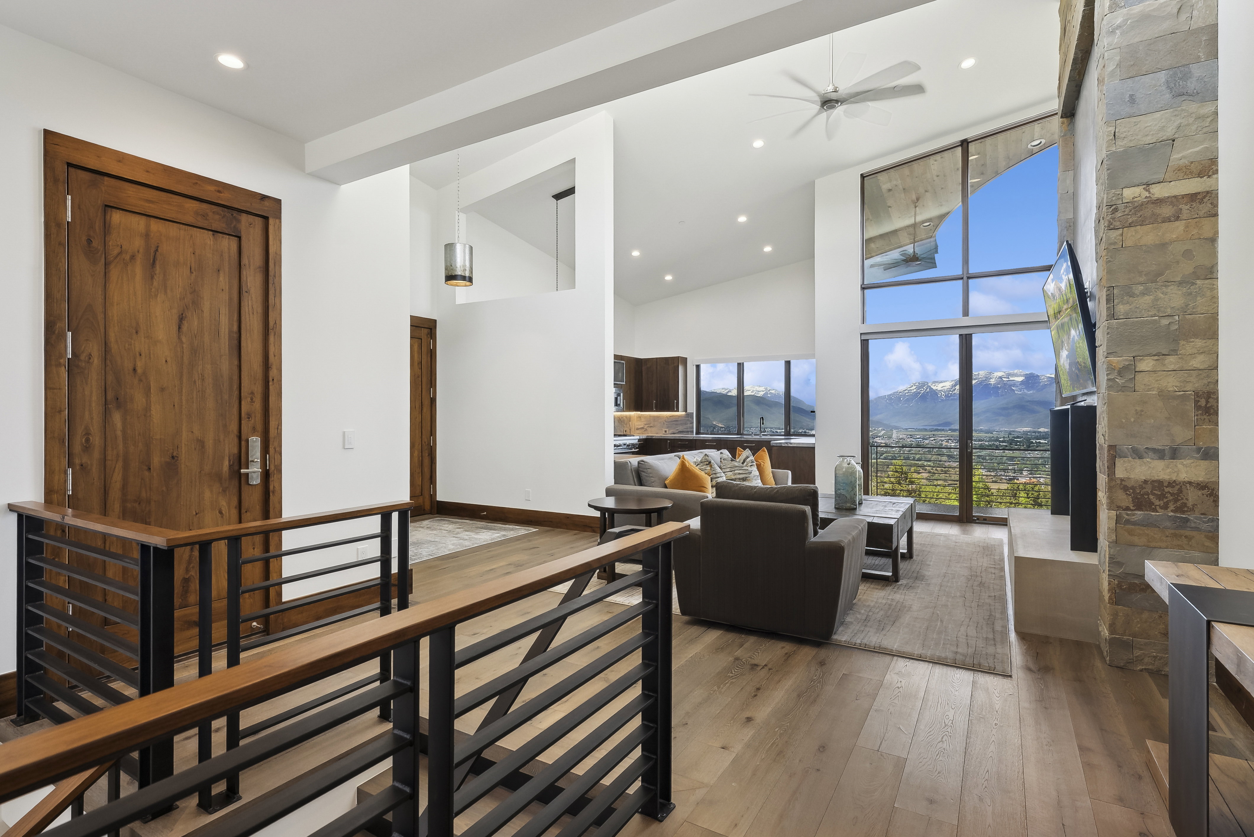 Open-concept living space with vaulted ceilings, a stone accent wall, and expansive windows offering mountain scenery