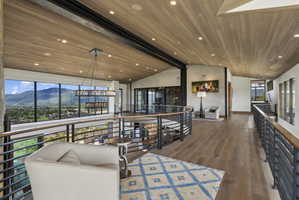 Upper level hallway featuring wood-finish flooring, a wood-paneled ceiling with recessed lighting, and a contemporary chandelier
