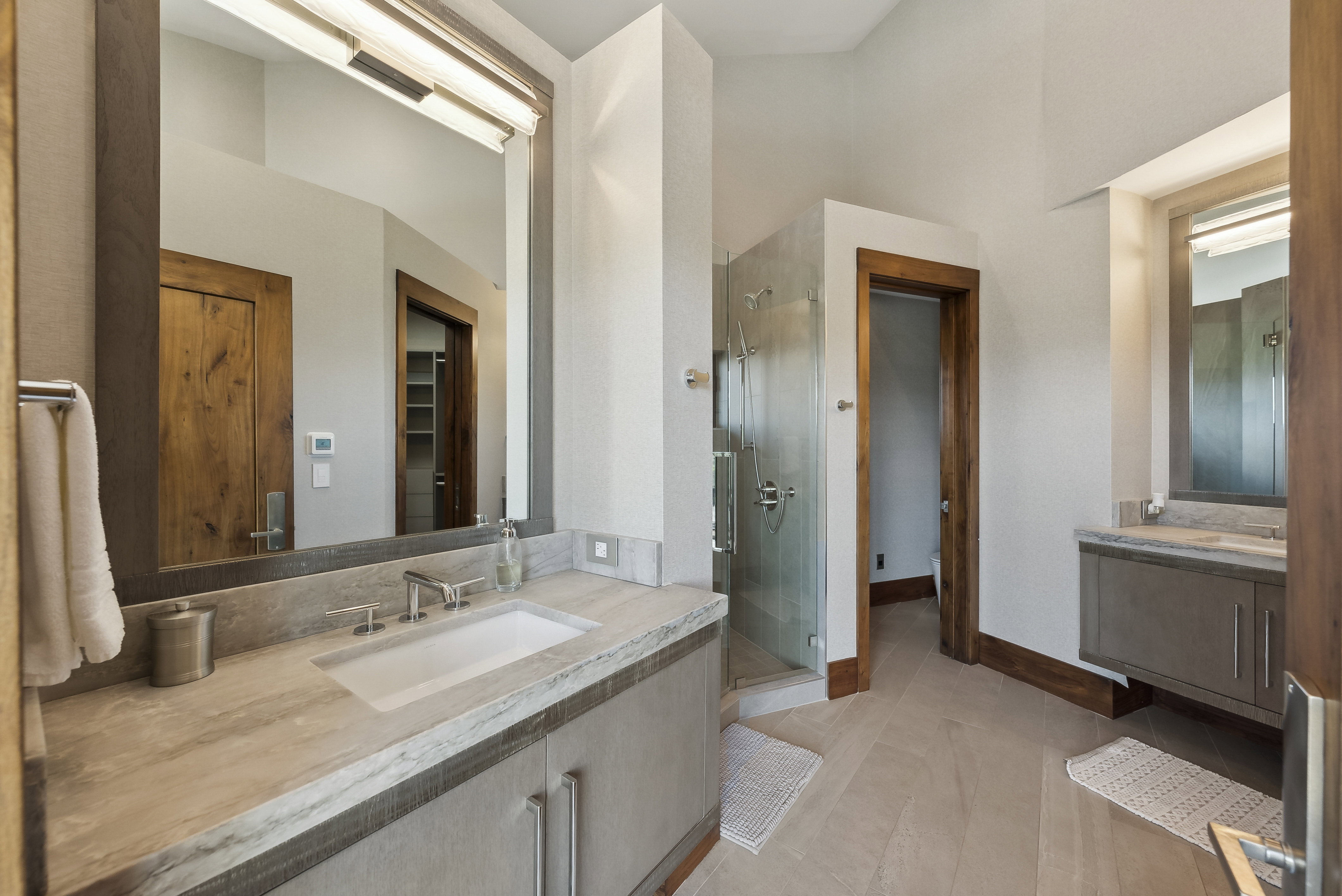Dual vanity bathroom featuring stone countertops, integrated rectangular sinks, and wood-finish flooring