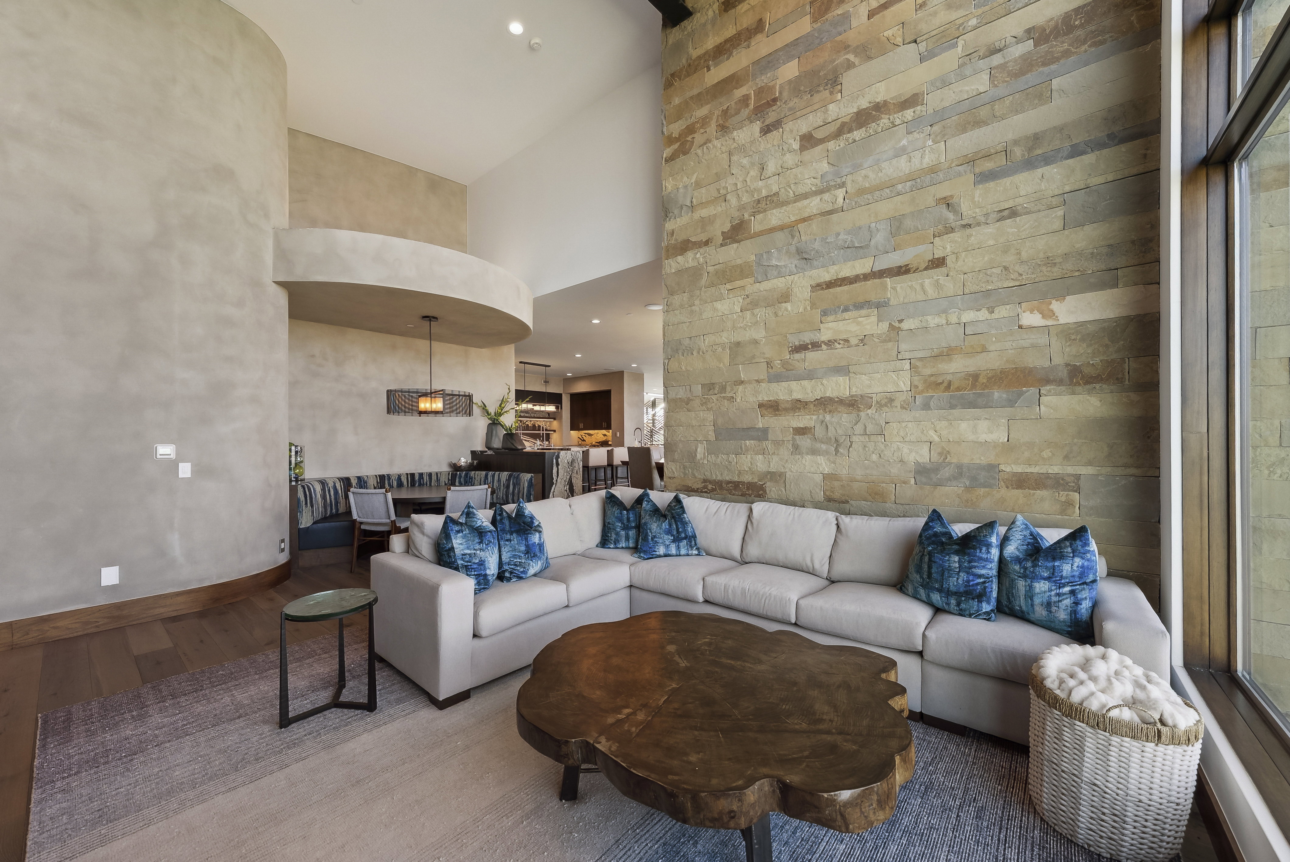 Great room featuring a natural stone accent wall, high ceilings, wood-finish flooring, and expansive windows