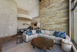 Great room featuring a natural stone accent wall, high ceilings, wood-finish flooring, and expansive windows