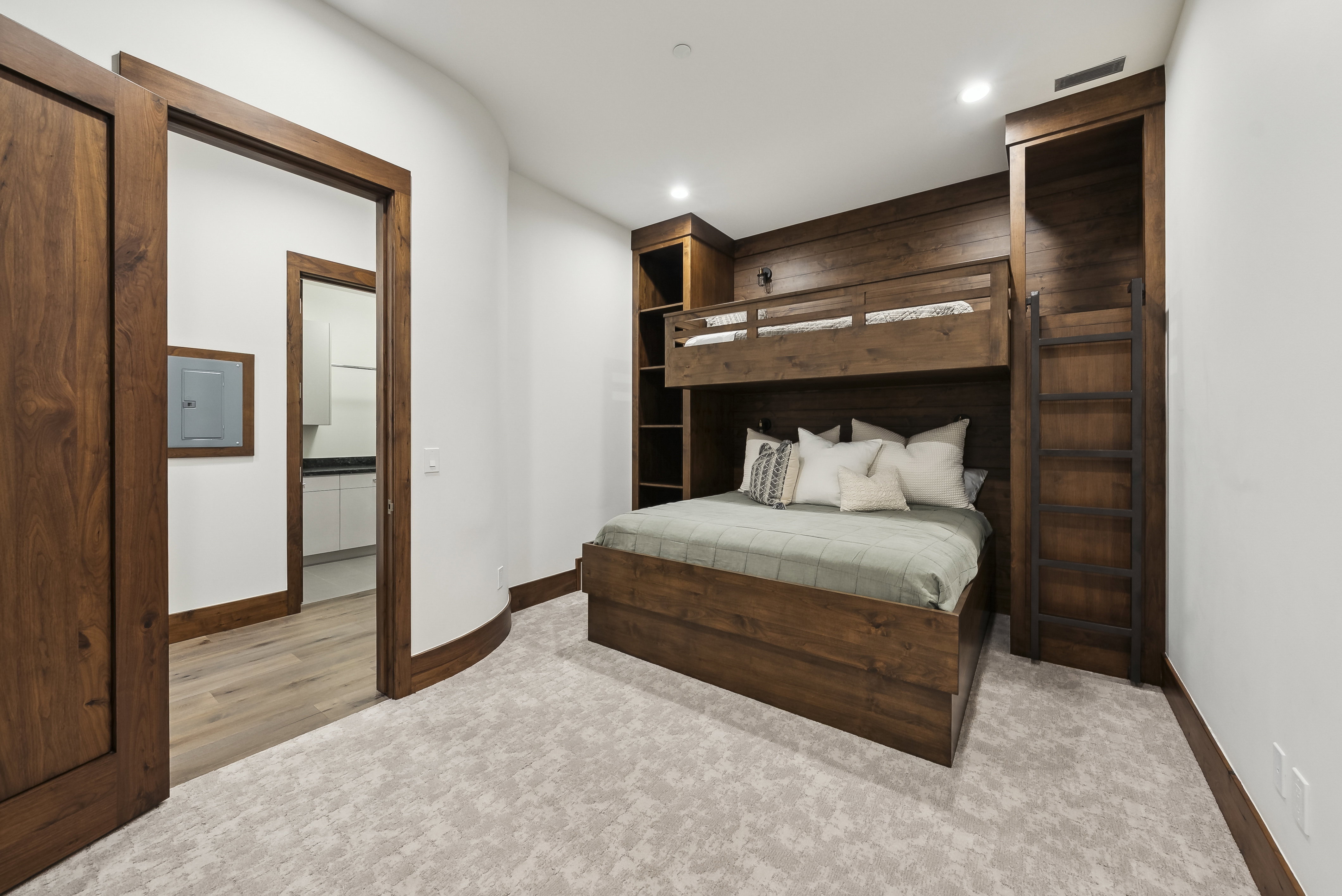Built-in wood-finish bunk beds with integrated shelving and a ladder