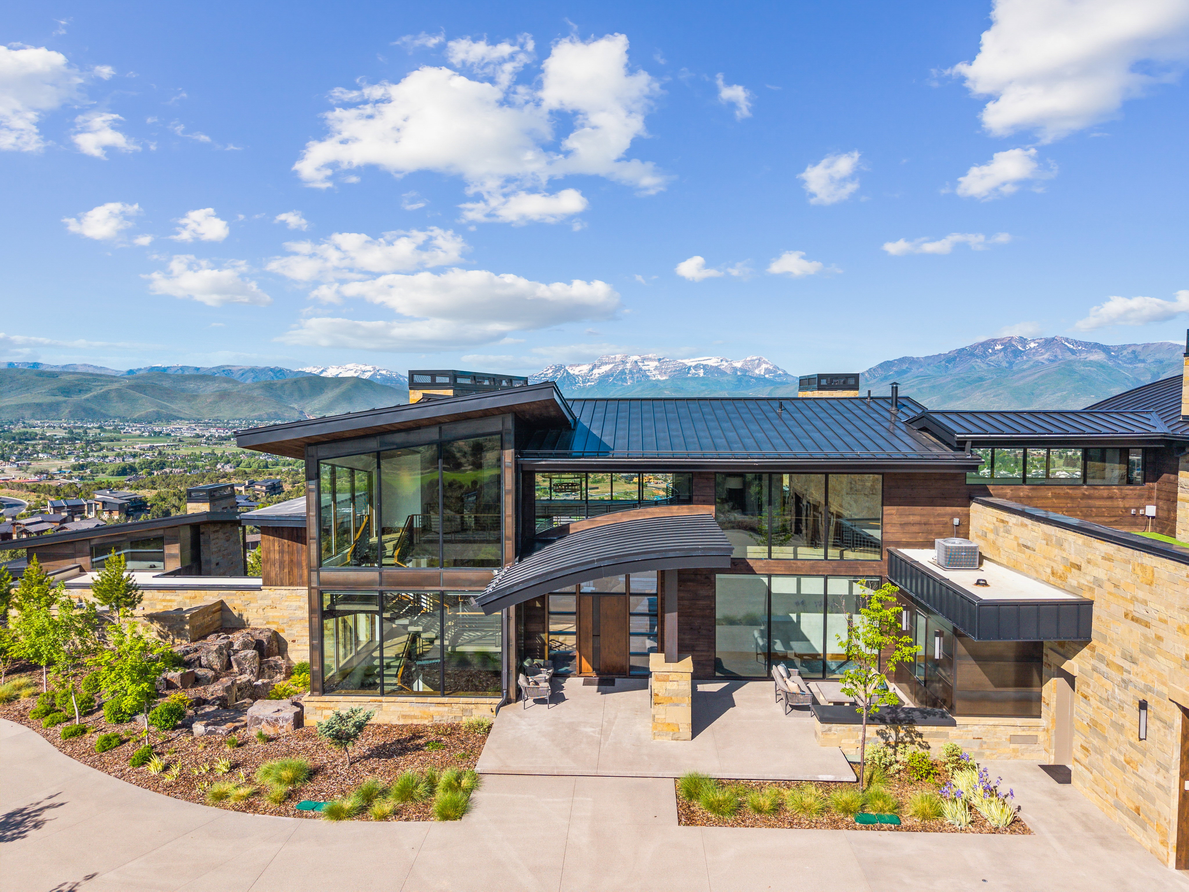 Modern architectural residence featuring extensive glazing, a standing seam metal roof, and stone facade accents