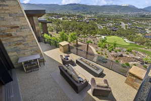 Expansive stone patio featuring a built-in fire pit, stone accent walls, and a visible golf green