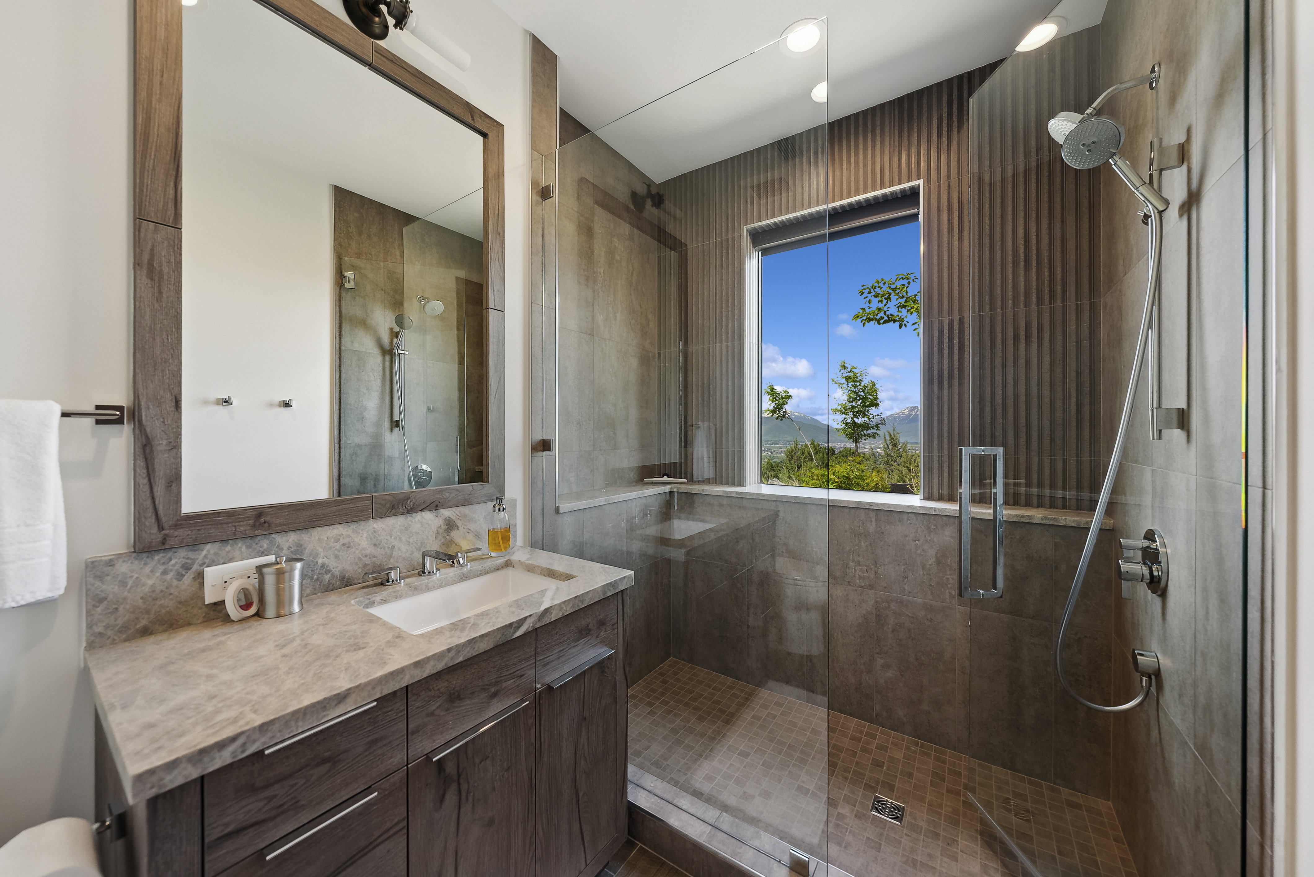 Modern bathroom featuring a wood-finish vanity with a light-toned countertop and an undermount sink