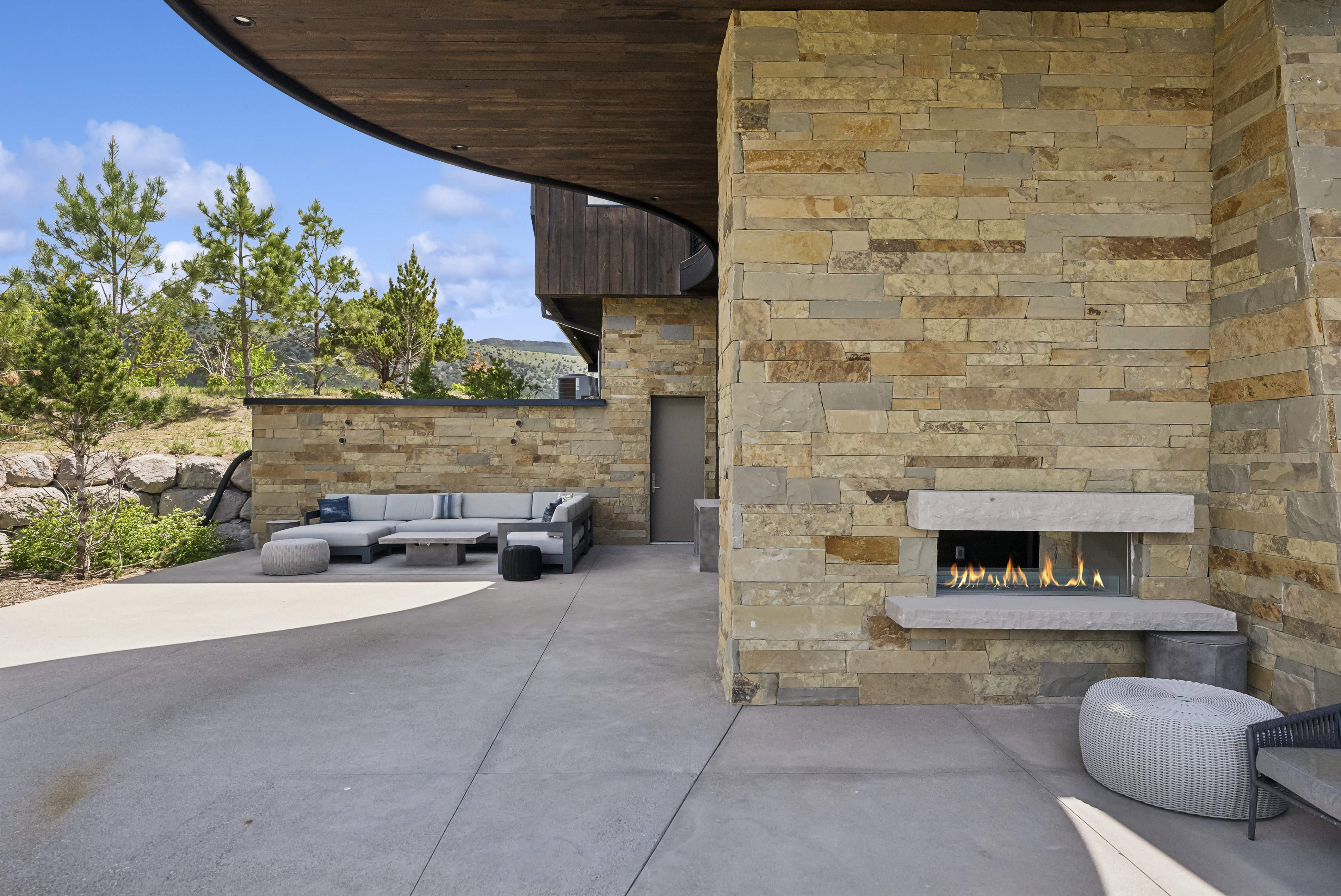 Stone-clad exterior wall featuring an integrated outdoor fireplace with a glass enclosure