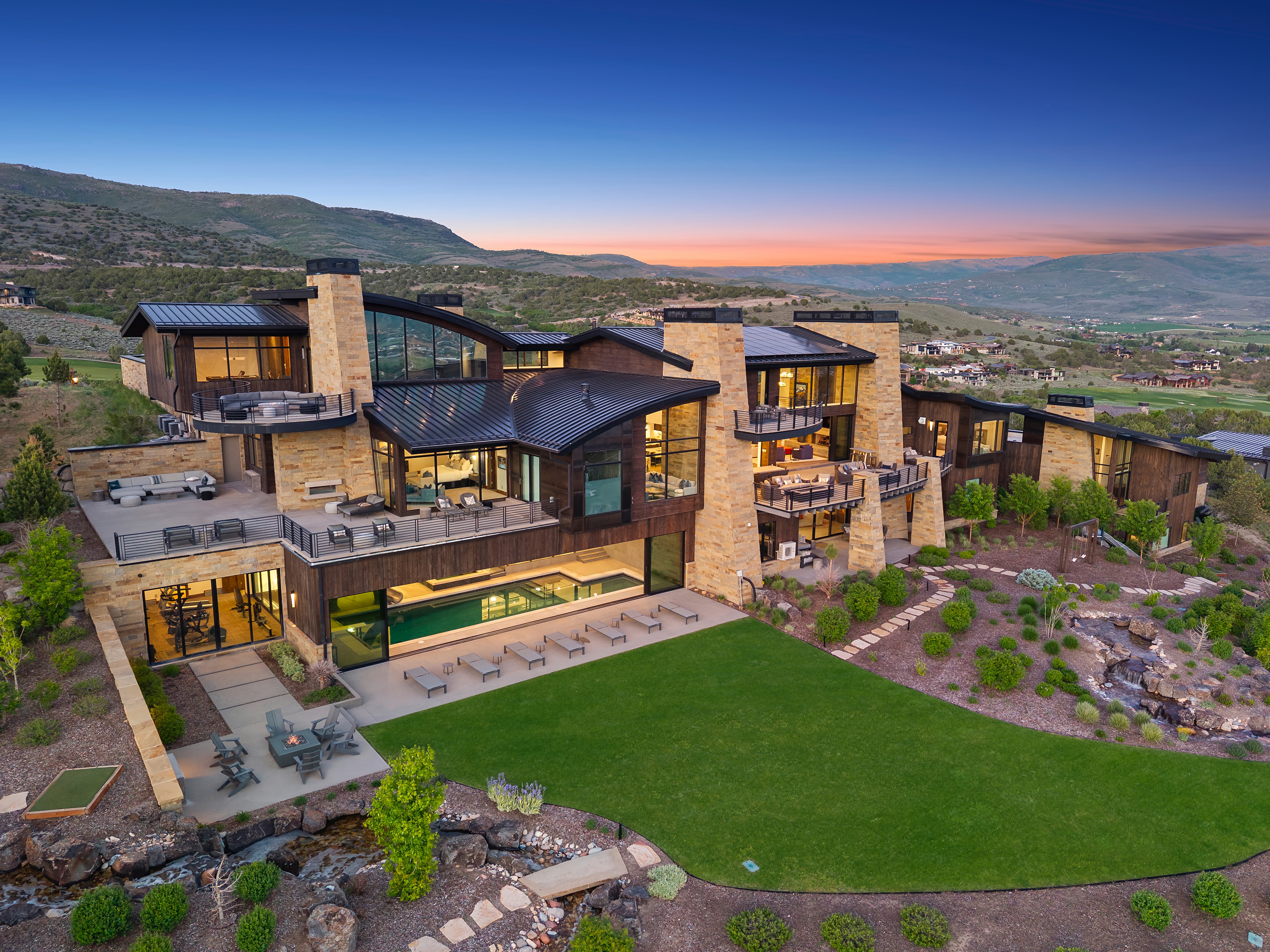 Expansive residence featuring multiple outdoor patios, a rectangular pool, and a manicured lawn