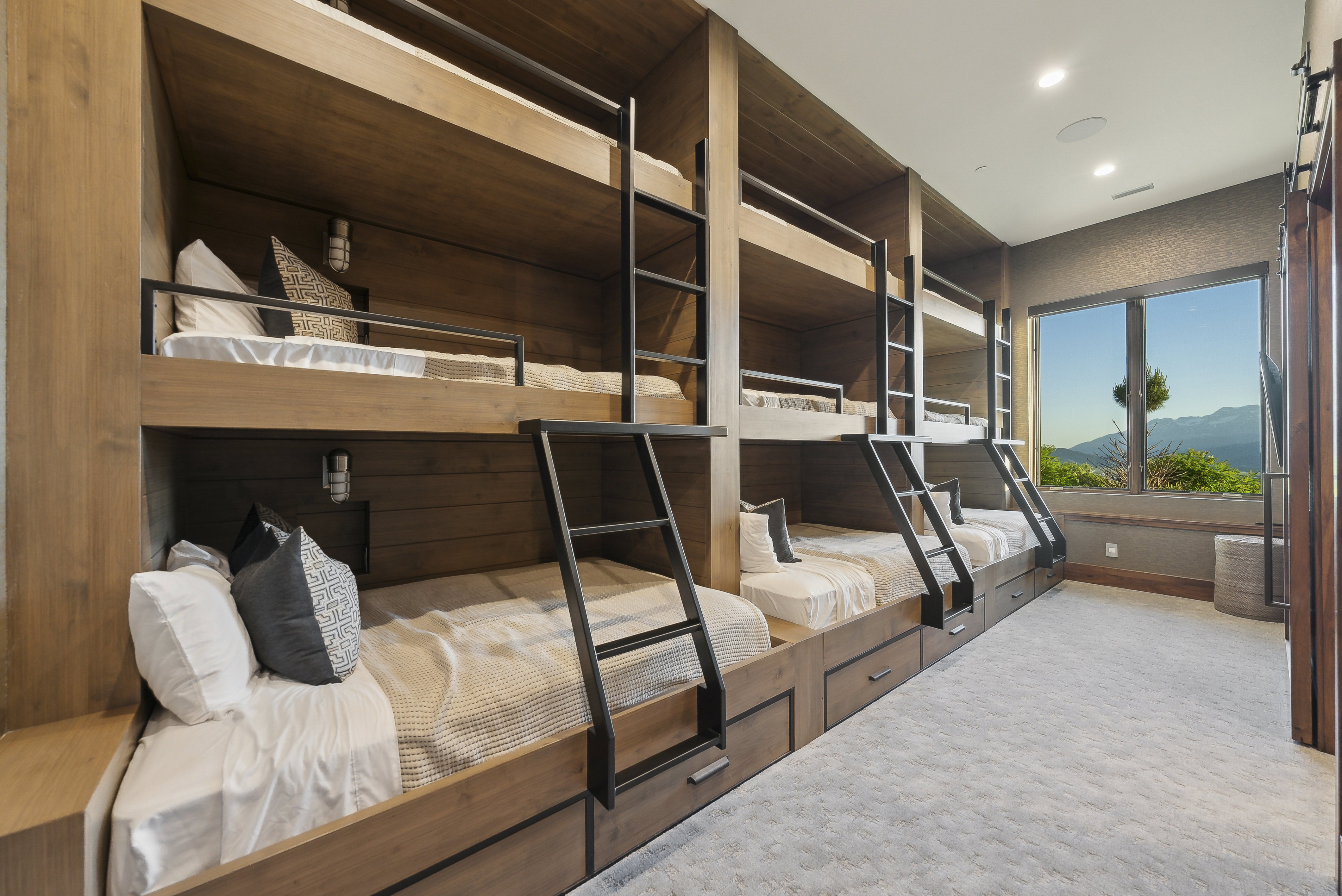 Custom built-in bunk beds crafted from natural wood-finish materials and dark metal accents