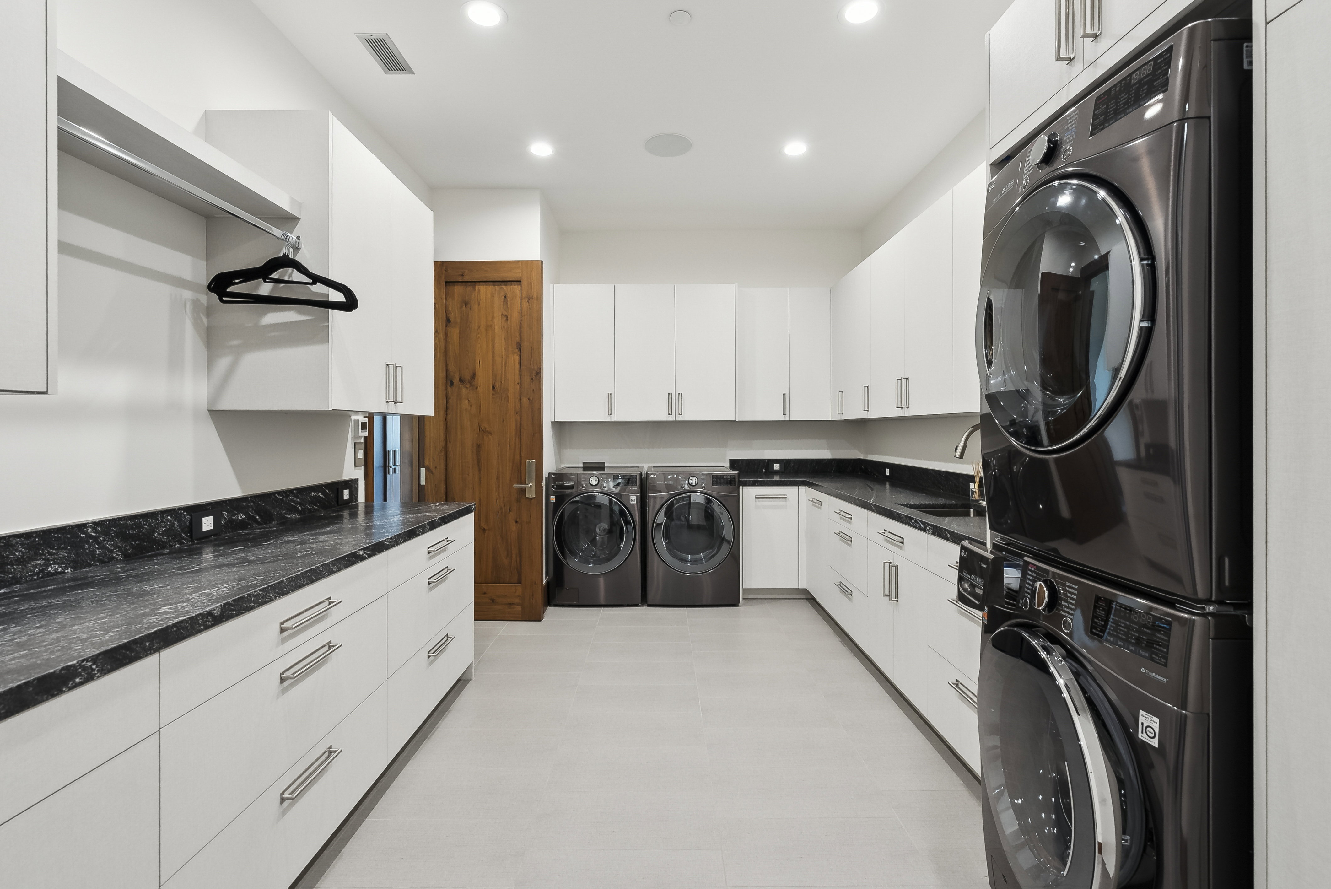 Dedicated laundry room featuring abundant white cabinetry, dark stone countertops, a single-basin sink, and recessed lighting