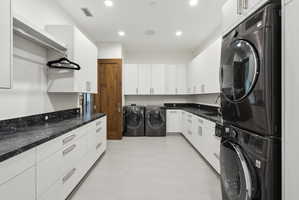 Dedicated laundry room featuring abundant white cabinetry, dark stone countertops, a single-basin sink, and recessed lighting