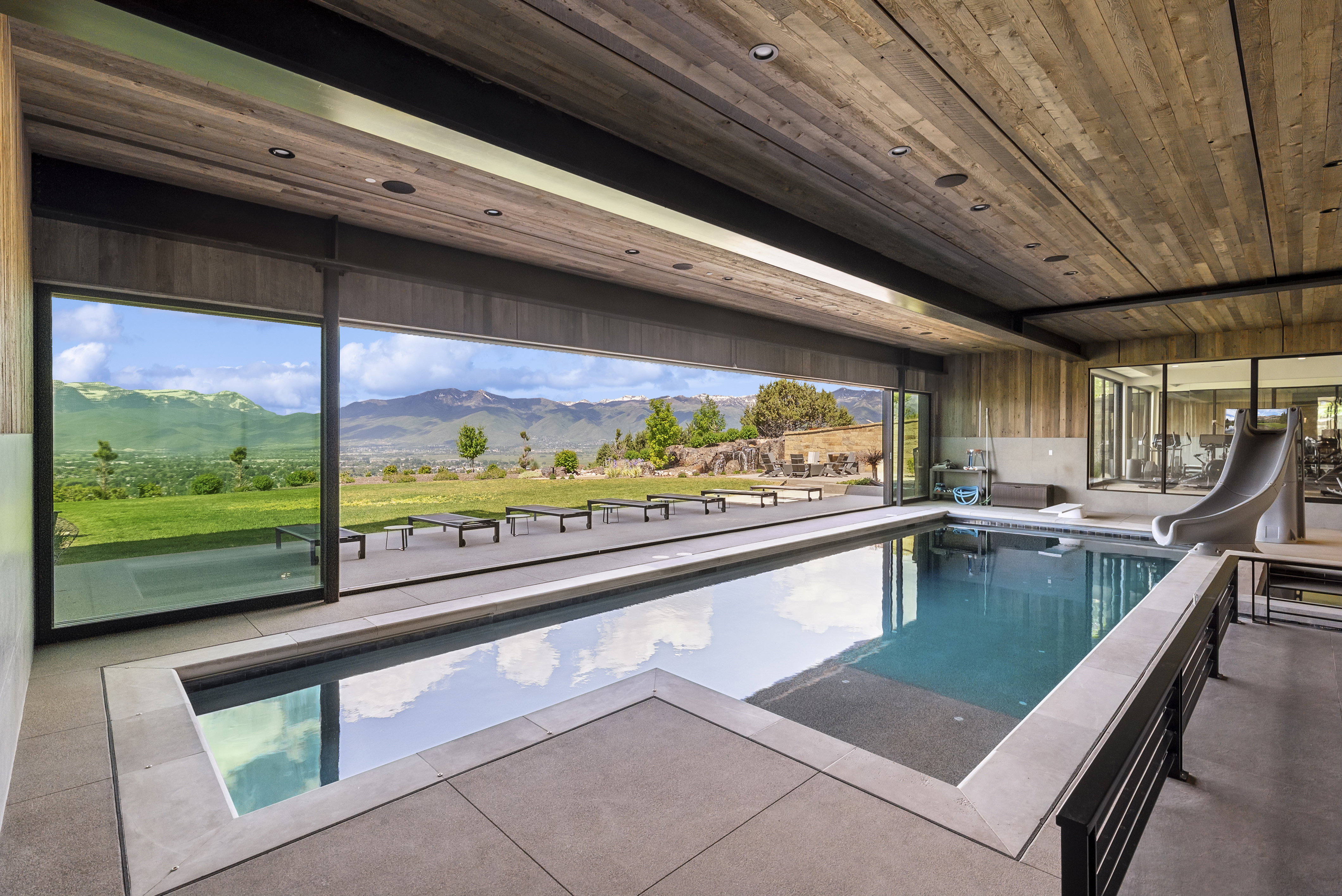 Indoor swimming pool featuring a built-in slide and extensive sliding glass panels