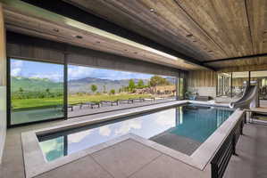 Indoor swimming pool featuring a built-in slide and extensive sliding glass panels