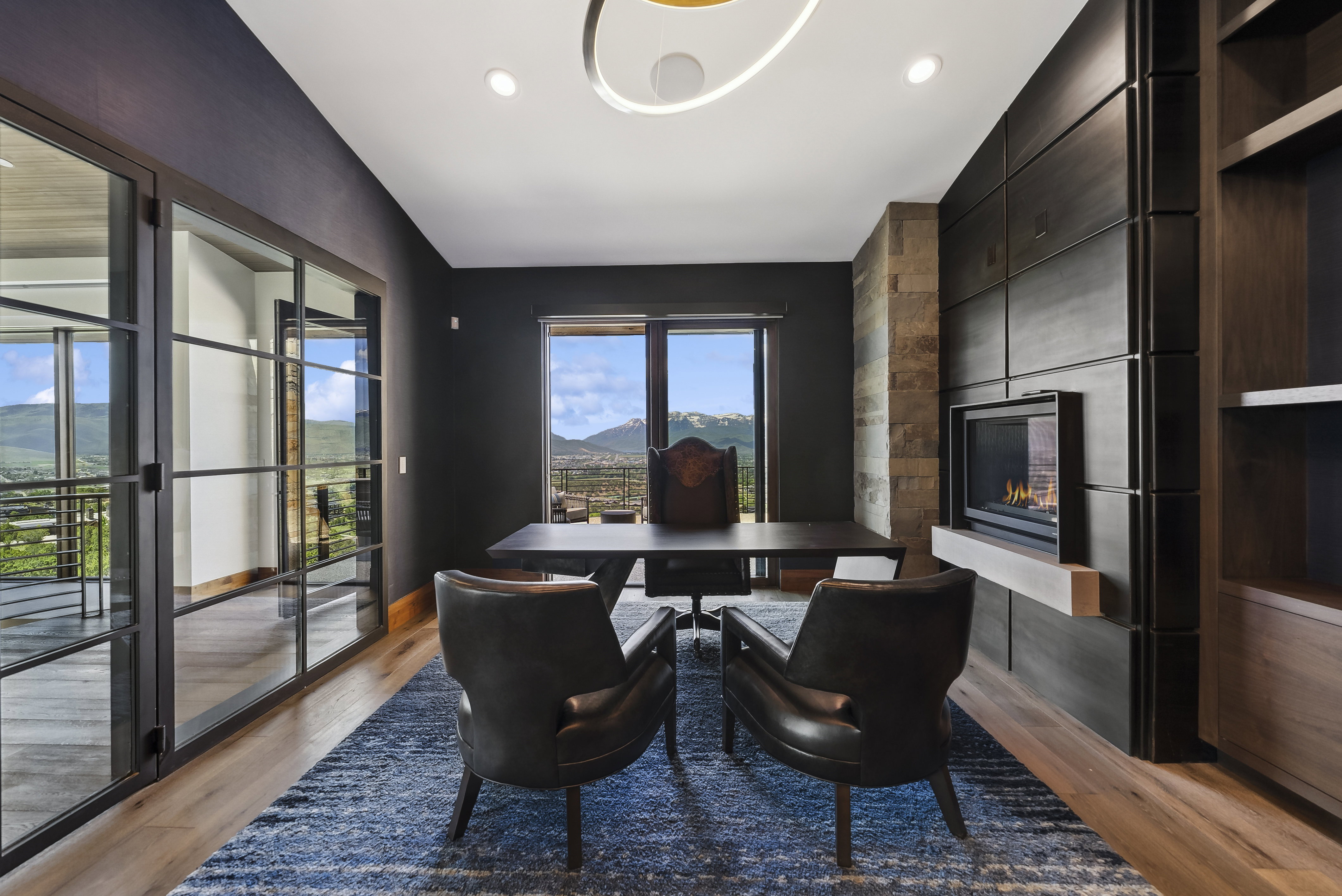 Modern office space featuring a built-in linear fireplace, stone accent wall, integrated dark wood cabinetry, and glass-paned doors
