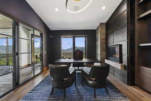 Modern office space featuring a built-in linear fireplace, stone accent wall, integrated dark wood cabinetry, and glass-paned doors
