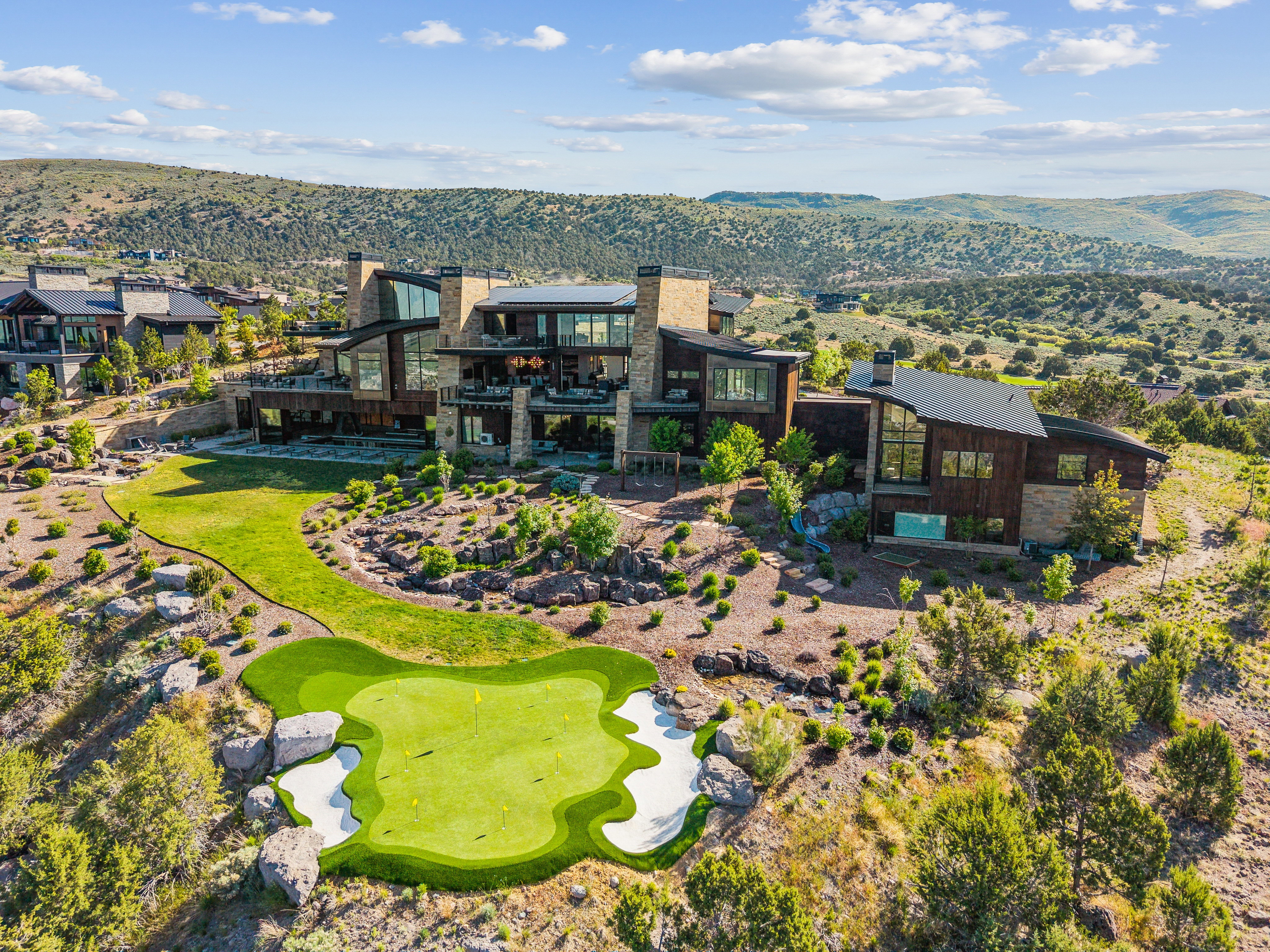 Modern architectural residence featuring extensive glazing, stone, and wood siding