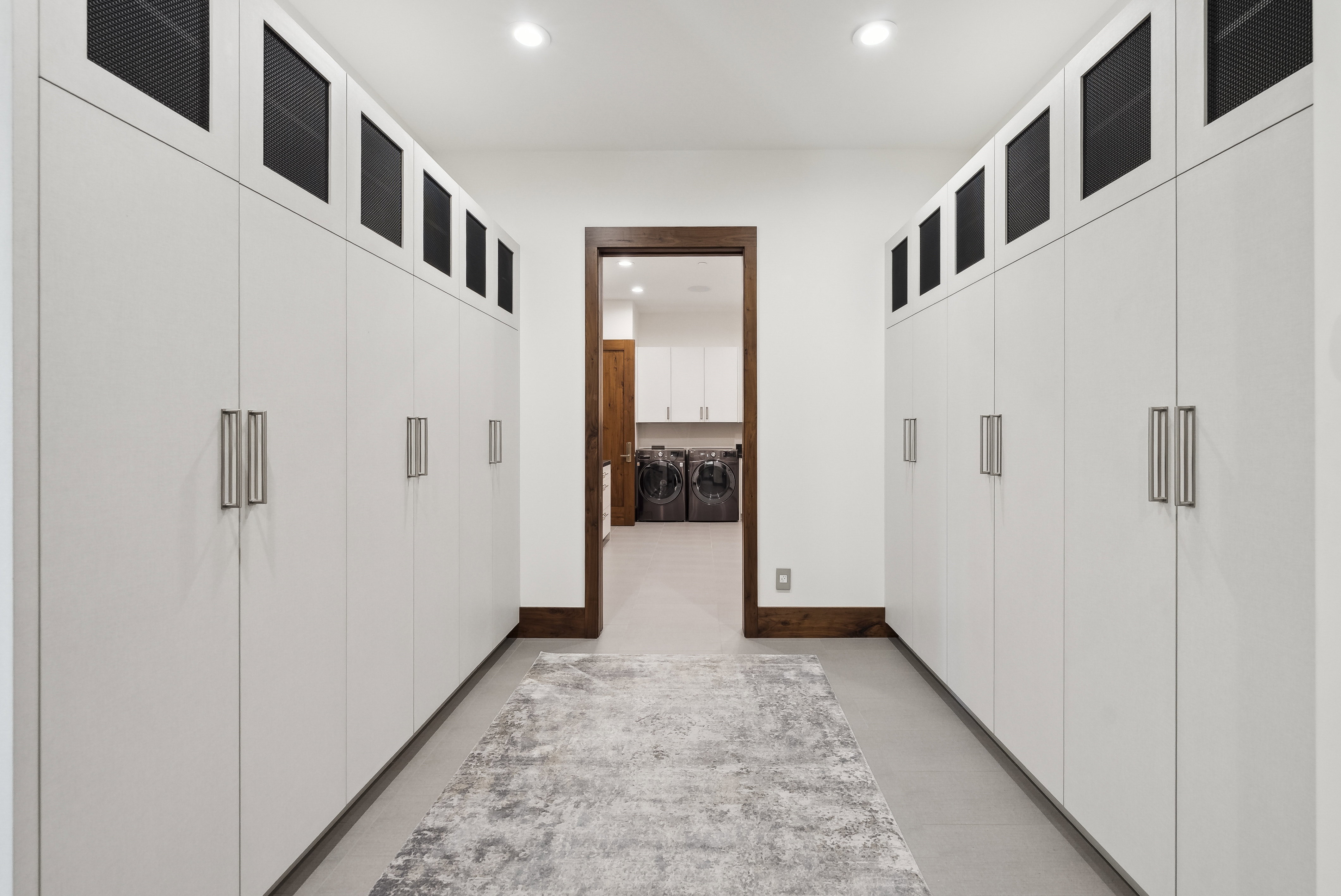 Hallway with extensive built-in cabinetry featuring sleek white doors and contemporary hardware